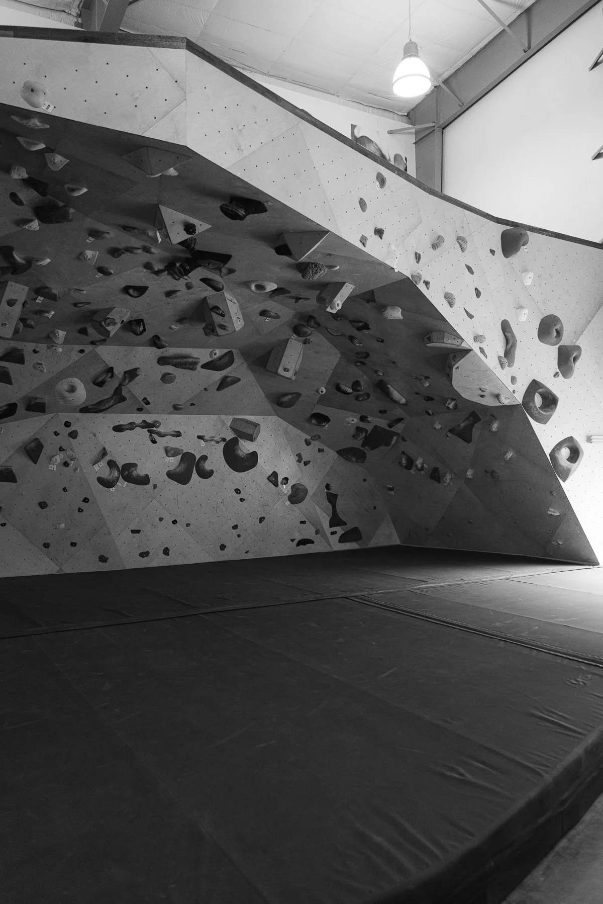 Black and white image of a bouldering wall with steep terrain and lots of climbing holds.