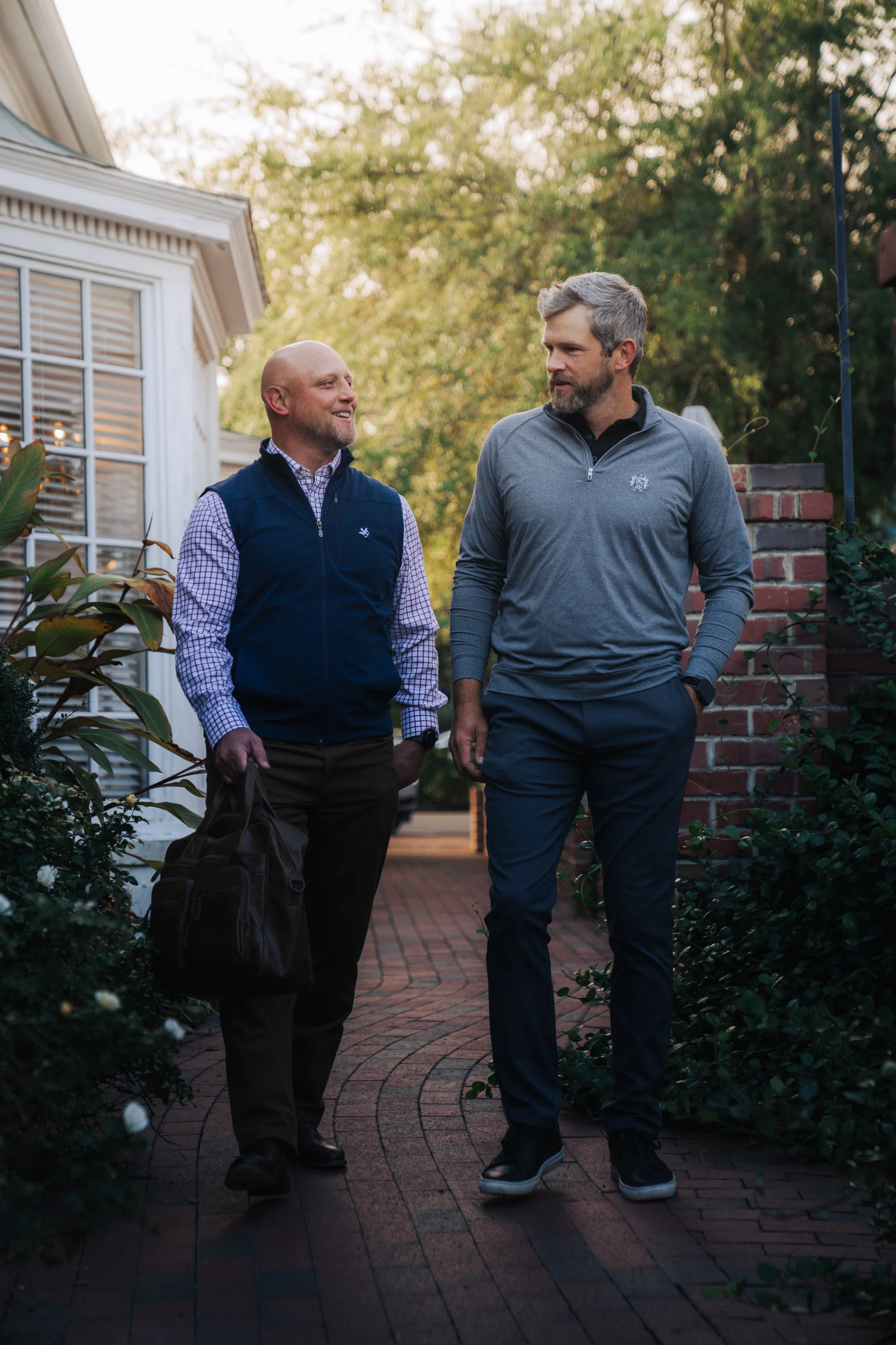 Adam Sanders walking alongside a client on a brick sidewalk.
