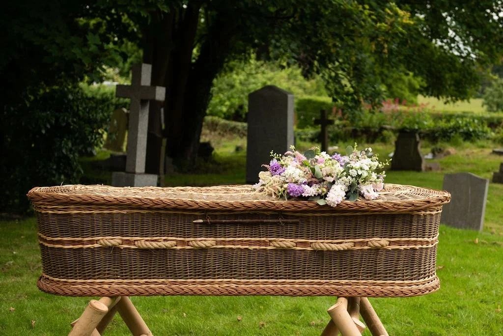 A natural wreath on a willow coffin in a graveyard.