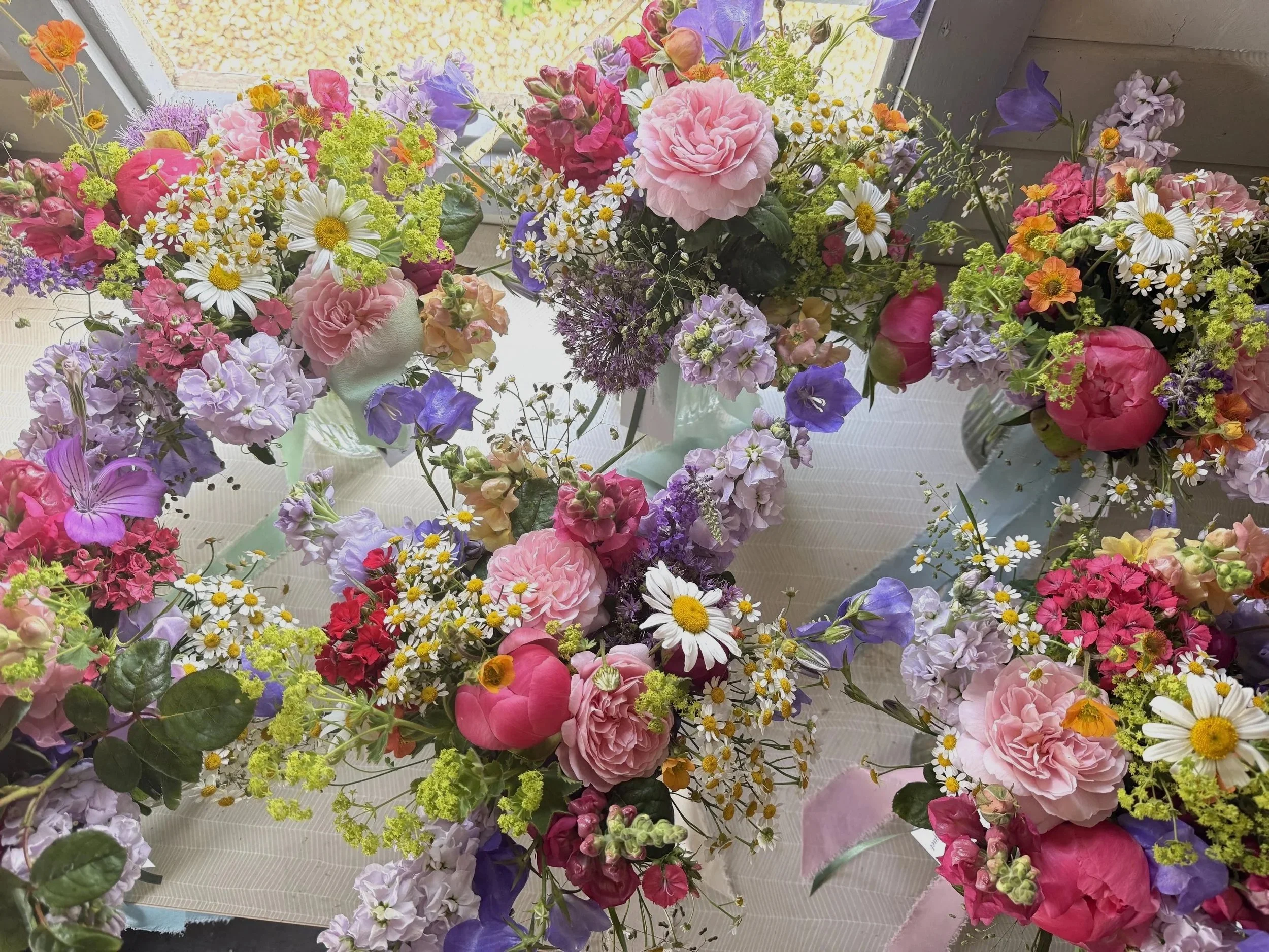 a picture of six wedding bouquets in bright June flowers