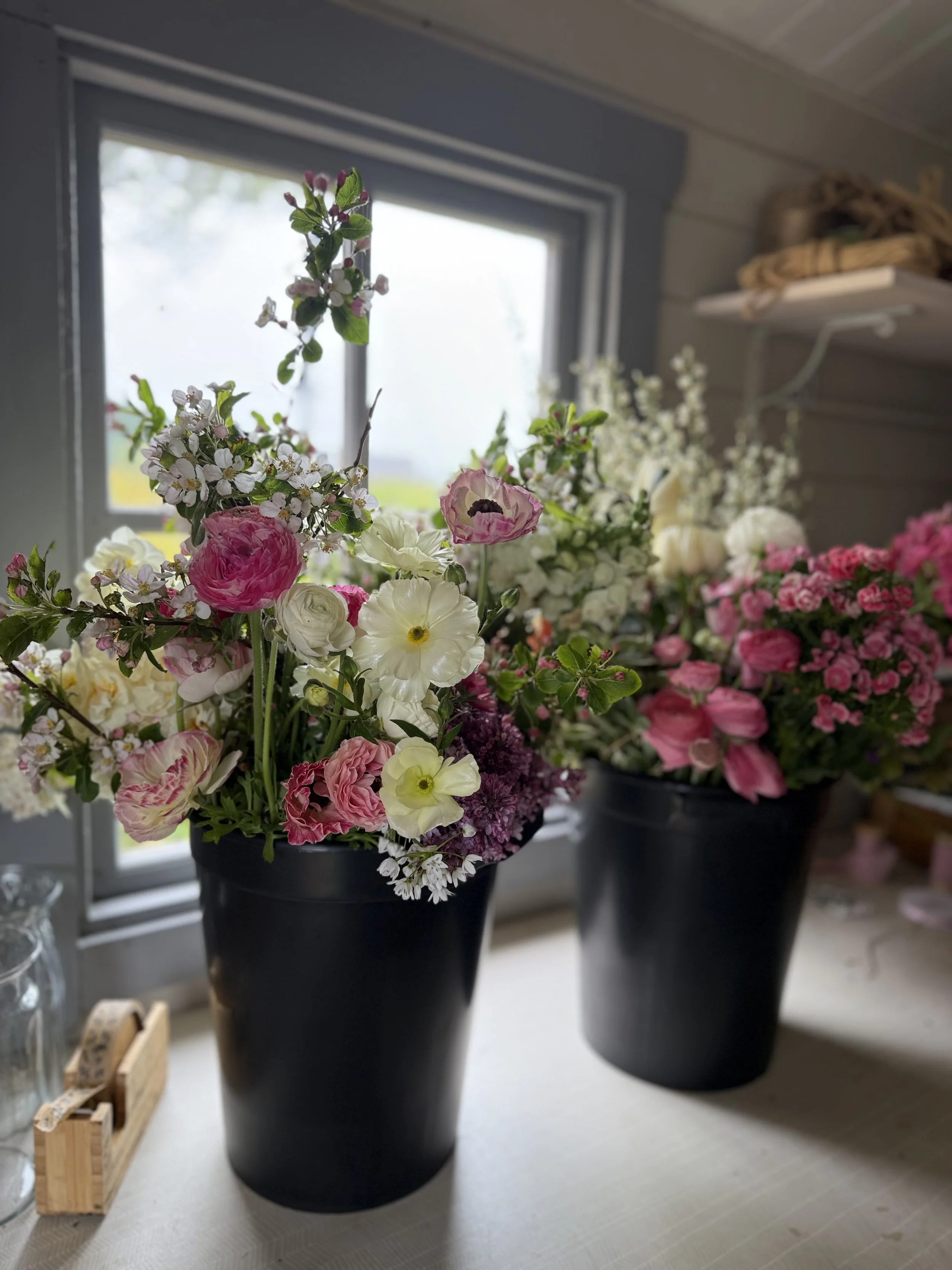 two buckets filled with flowers ready for a couople to arrange themselves for their wedding day.