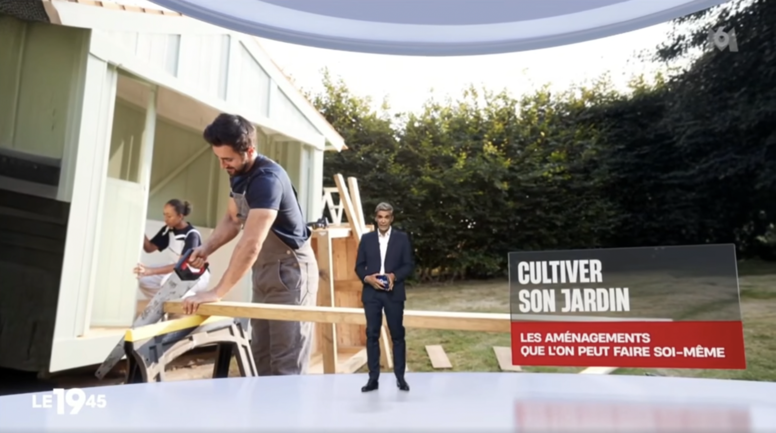 Une personne est en train de construire ou réparer une structure en bois dans un jardin, avec deux autres personnes observant ou supervisant. Le panneau indique qu'il s'agit d'un projet de jardinage DIY.