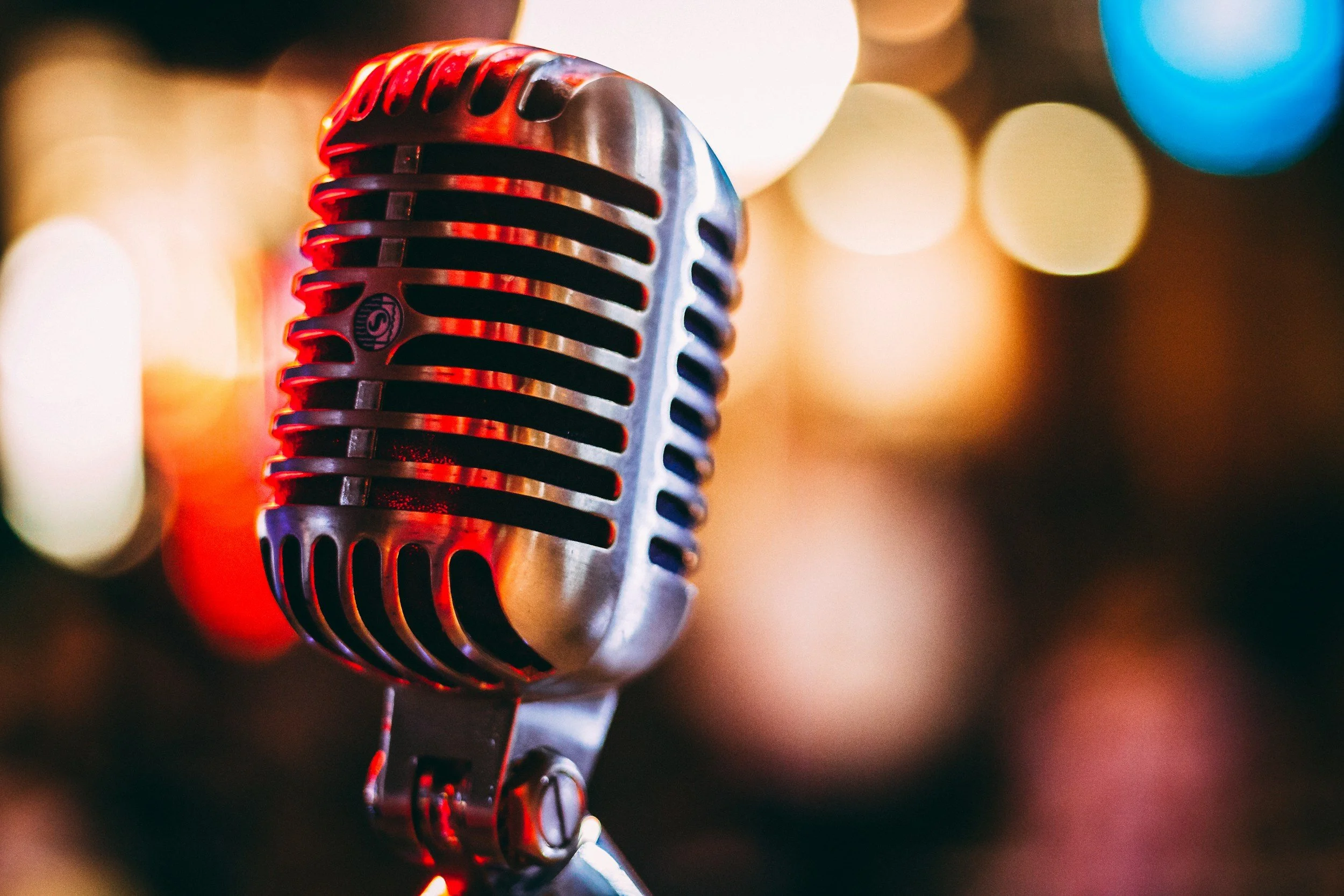 Close-up of a vintage microphone with a colorful bokeh background.