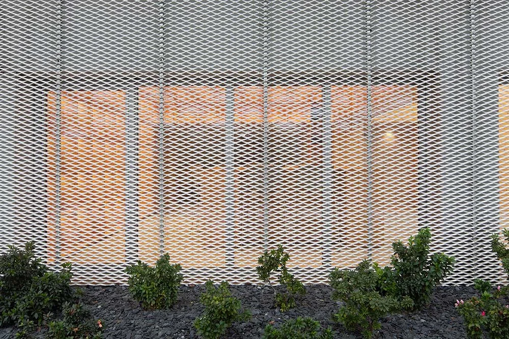 Vara de metal com fundo de vidro fosco, com plantas verdes na parte inferior.