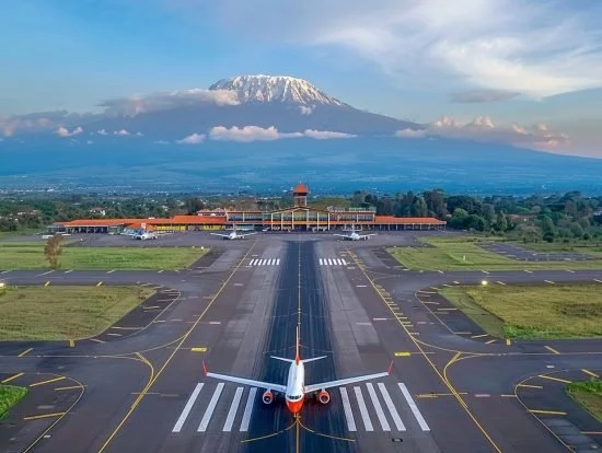 An airplane on a taxiway ready for takeoff at an airport, with a mountain in the background.