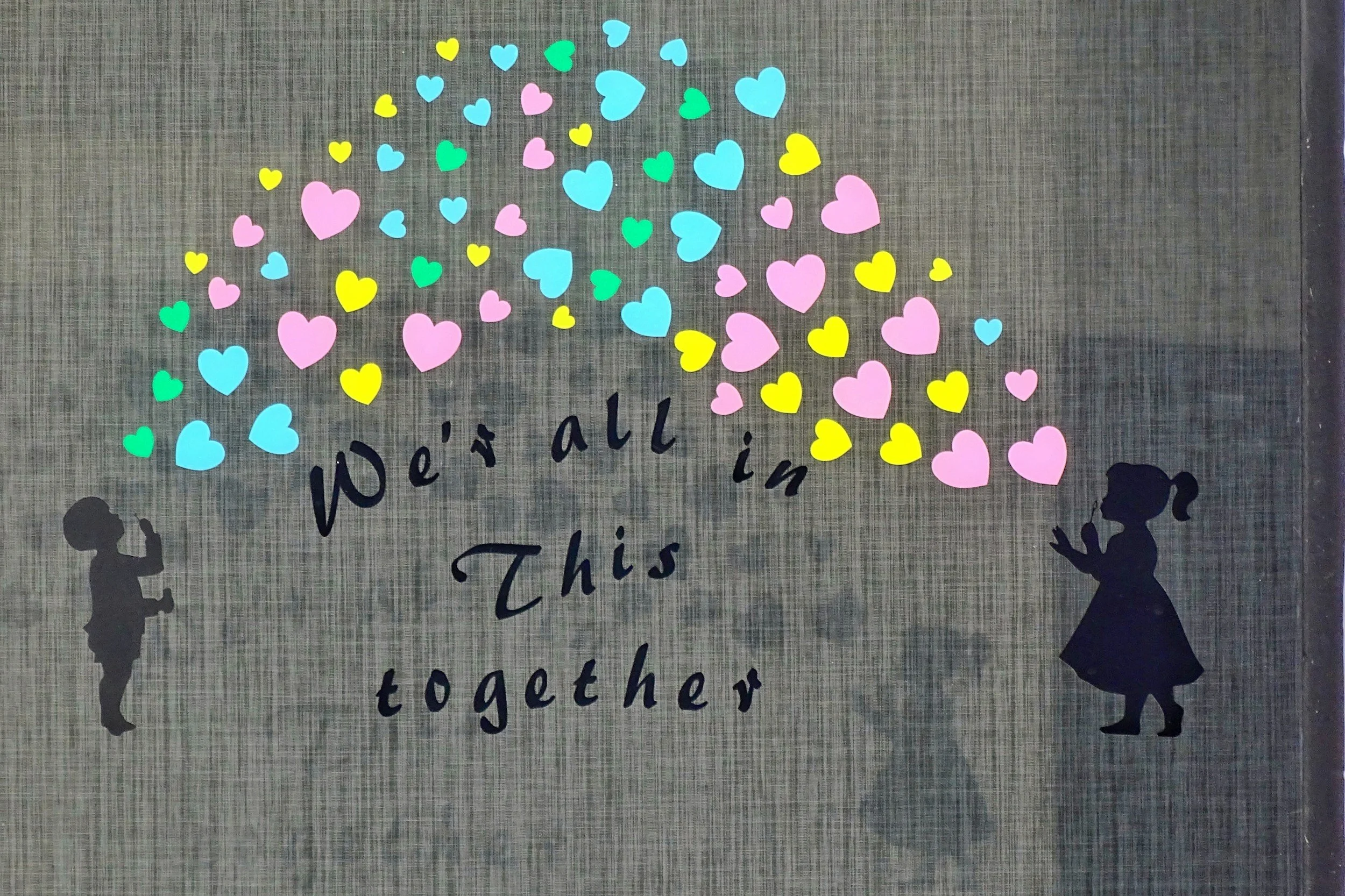 Artwork with colorful hearts and the words we are all in this together, representing compassion and support