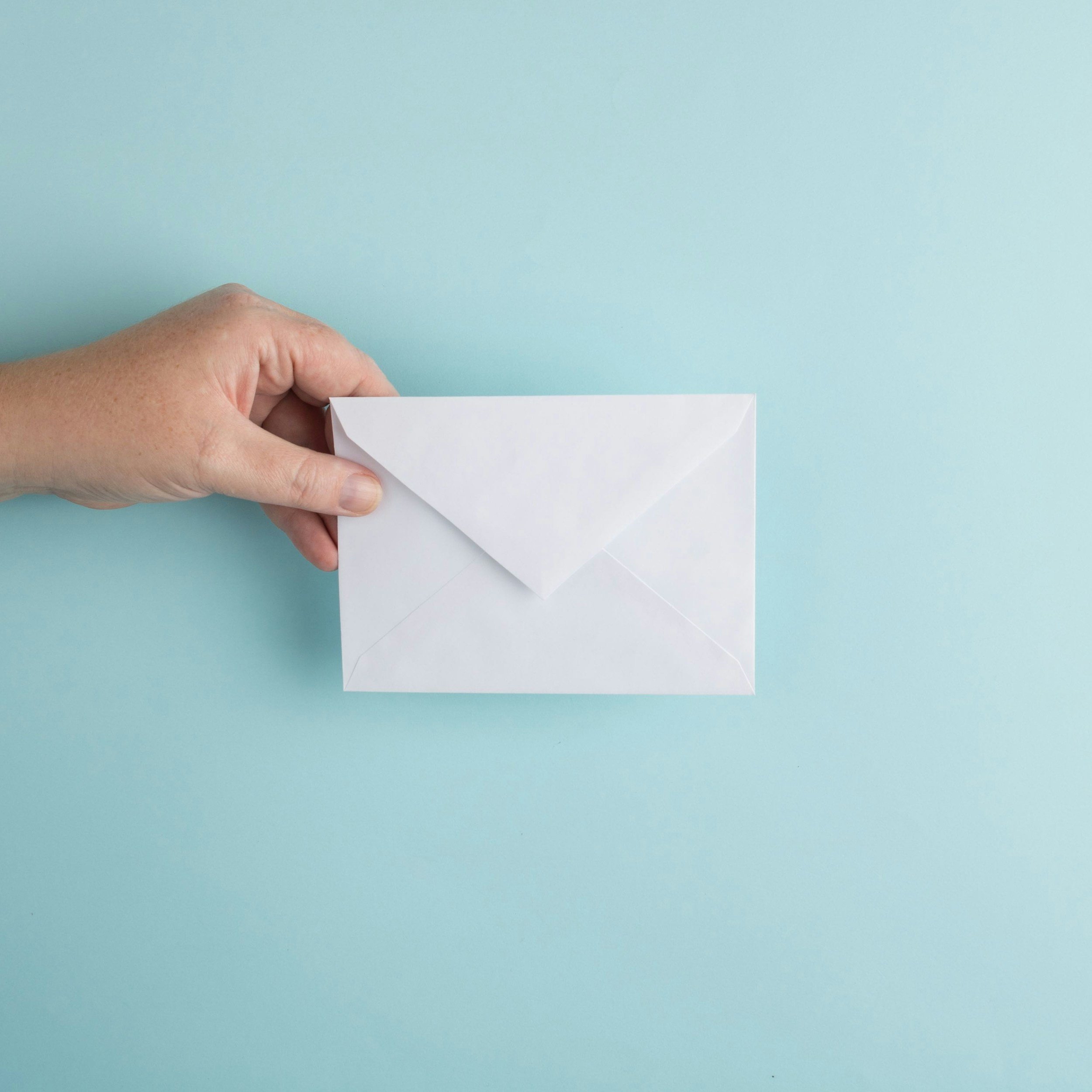 Hand holding a white envelope, representing contacting NewPathNeuro for questions, resources, or support