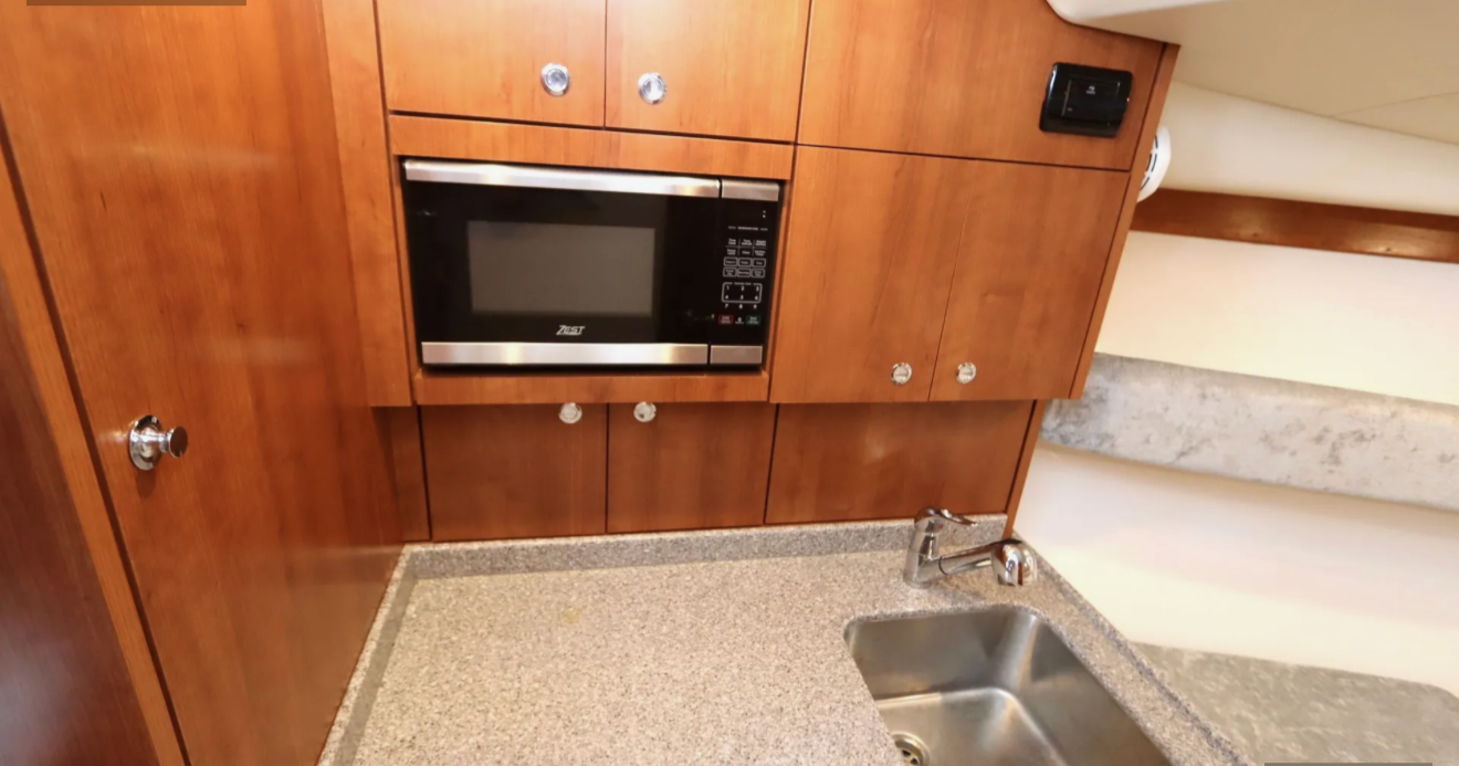 Kitchen with wooden cabinets, a built-in microwave, a granite countertop, and a stainless steel sink.