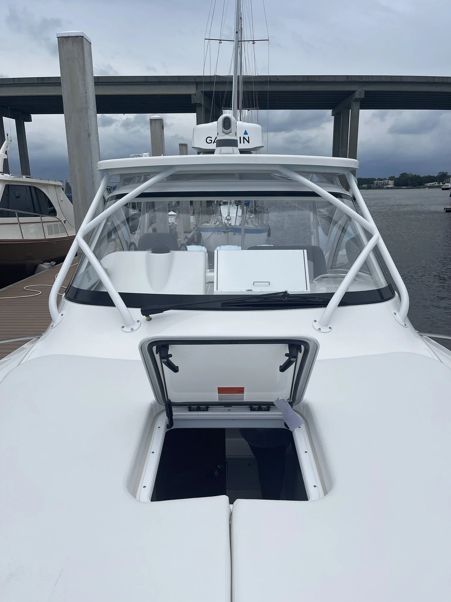 View of a white boat docked at a marina with a clear hatch open on the roof, showing the boat's interior.