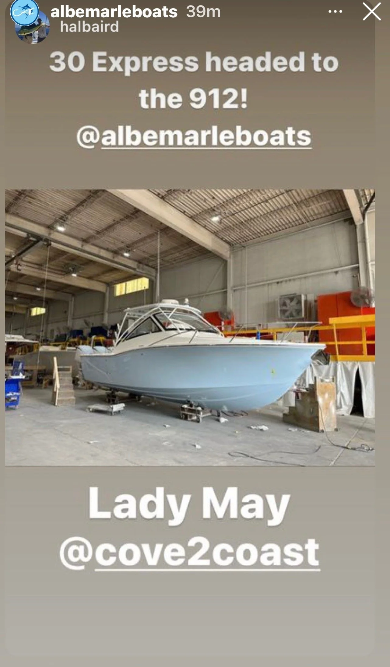 Indoor boat warehouse with a boat on a stand, surrounded by equipment and industrial shelves.
