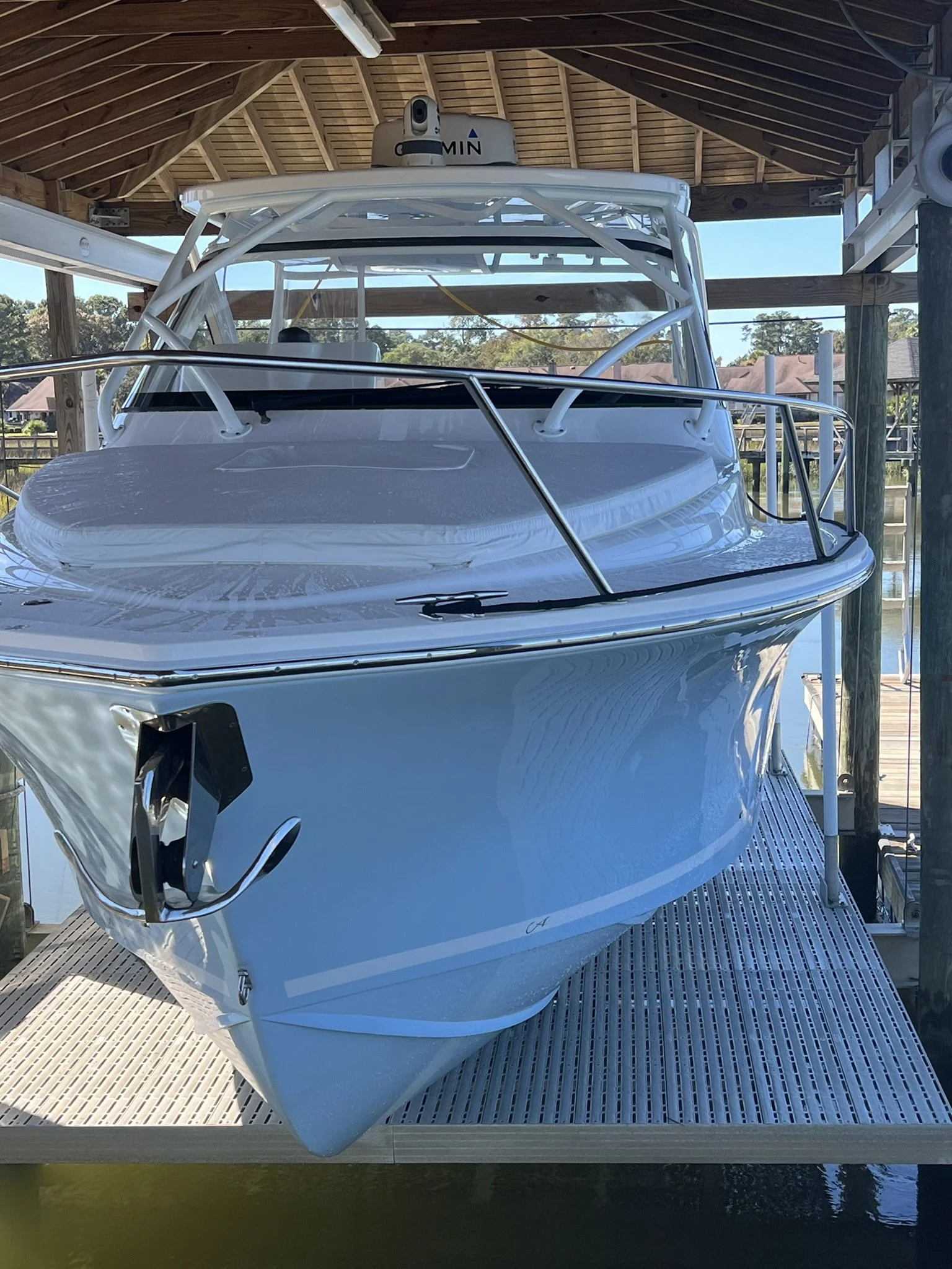 A white yacht docked in a covered marina with a wooden roof and water below.