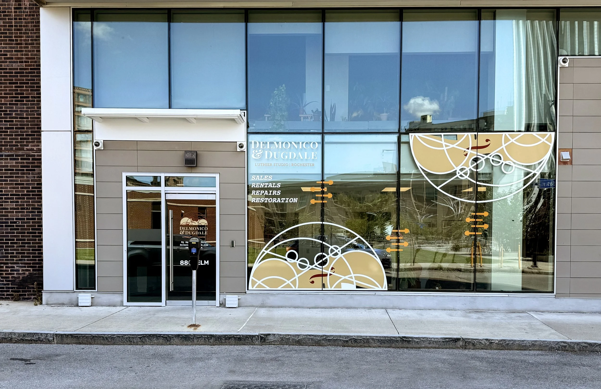 front of downtown Rochester violion luthier shop with a glass facade and Delmonico & Dugdale window decals
