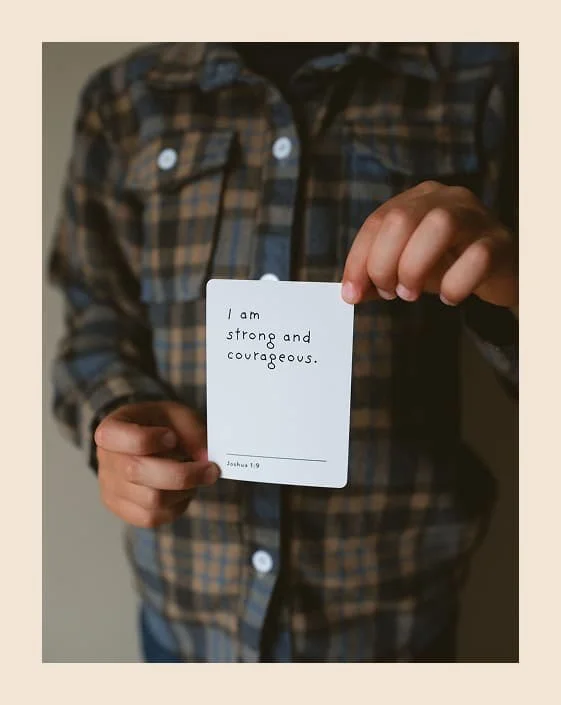 Child holding an affirmation card that reads 'I am strong and courageous,' used in kids therapy sessions at The Haven