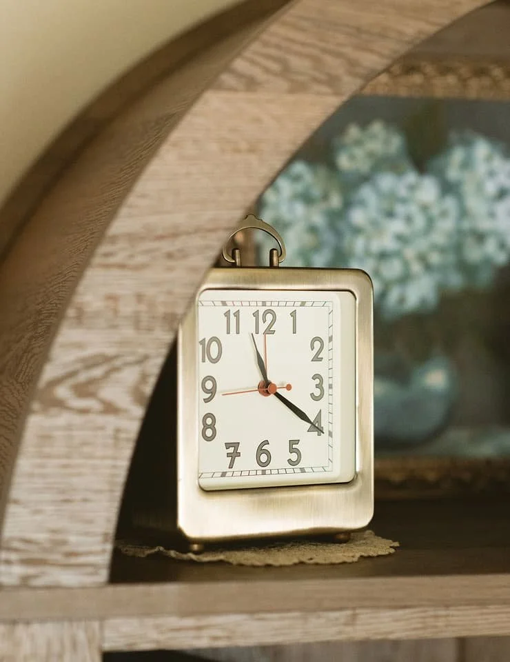 Vintage brass clock displayed on a wooden shelf at The Haven