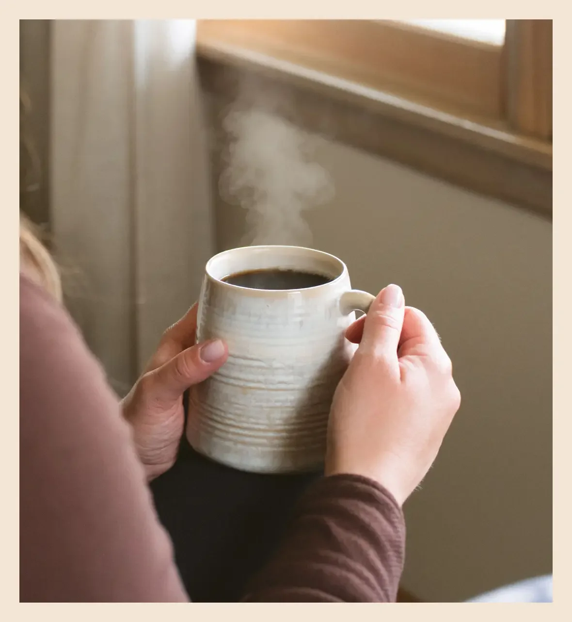 Woman quietly holding a warm mug of coffee, a small moment of stillness amid emotional exhaustion