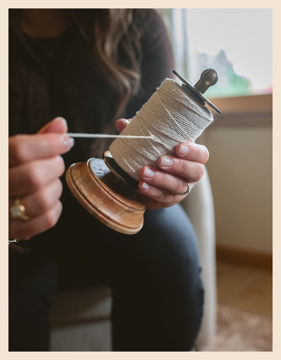 Close-up of hands winding thread on a vintage wooden spool, a detail shot from The Haven's about page