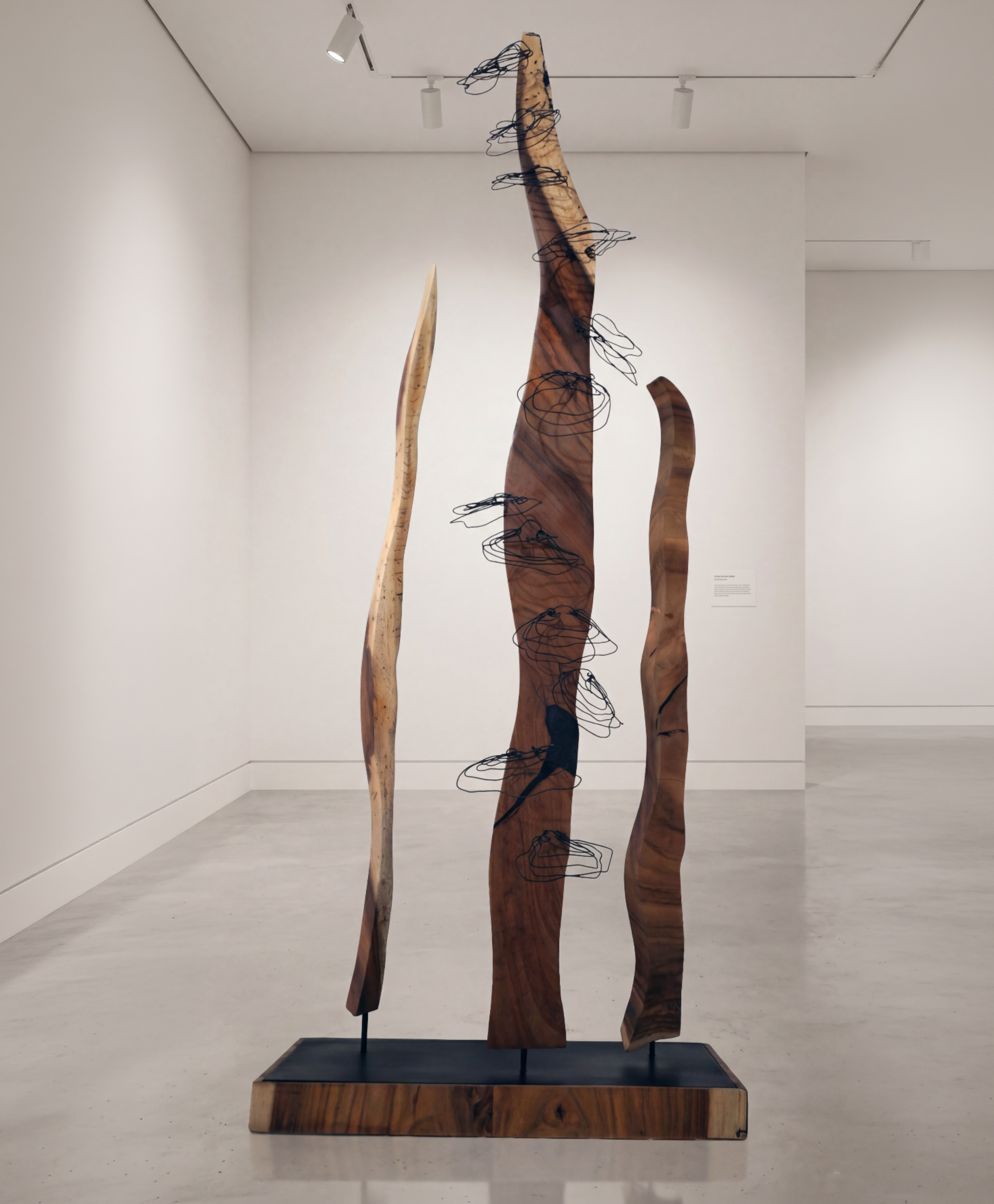 Wooden sculpture with black wire in a gallery space.
