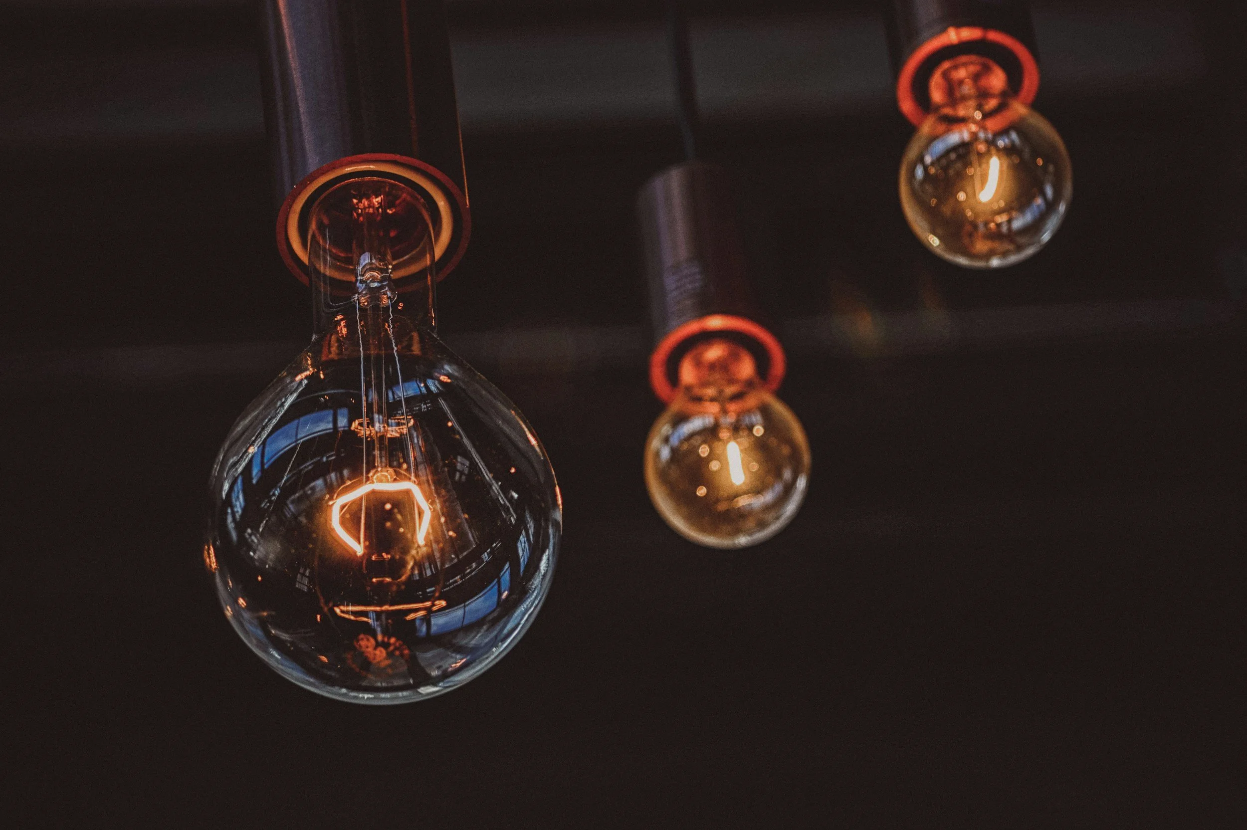 Ampoules à filament incandescent suspendues au plafond avec une lumière chaude, reflet dans le verre, ambiance sombre