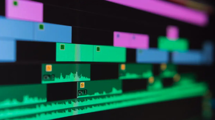Close-up of digital editing workstation timeline with colorful audio and video tracks and waveform visualizations.