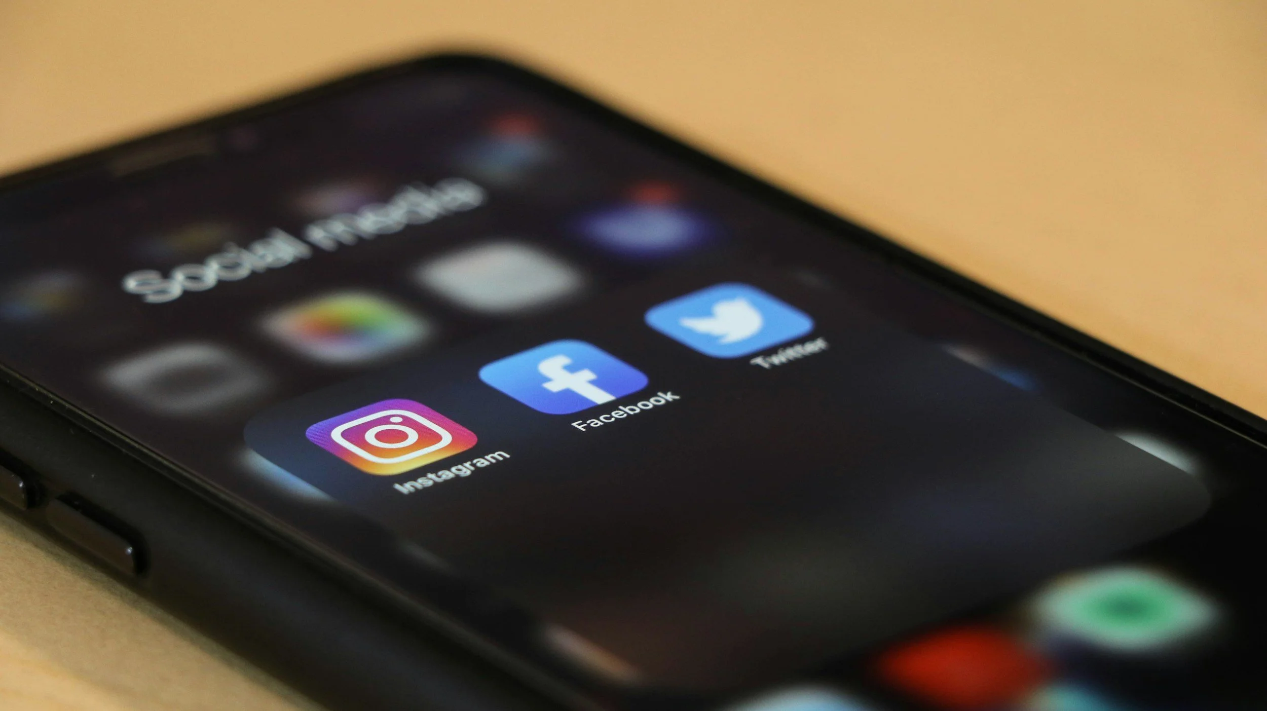 Close-up of a smartphone screen displaying social media app icons for Instagram, Facebook, and Twitter.