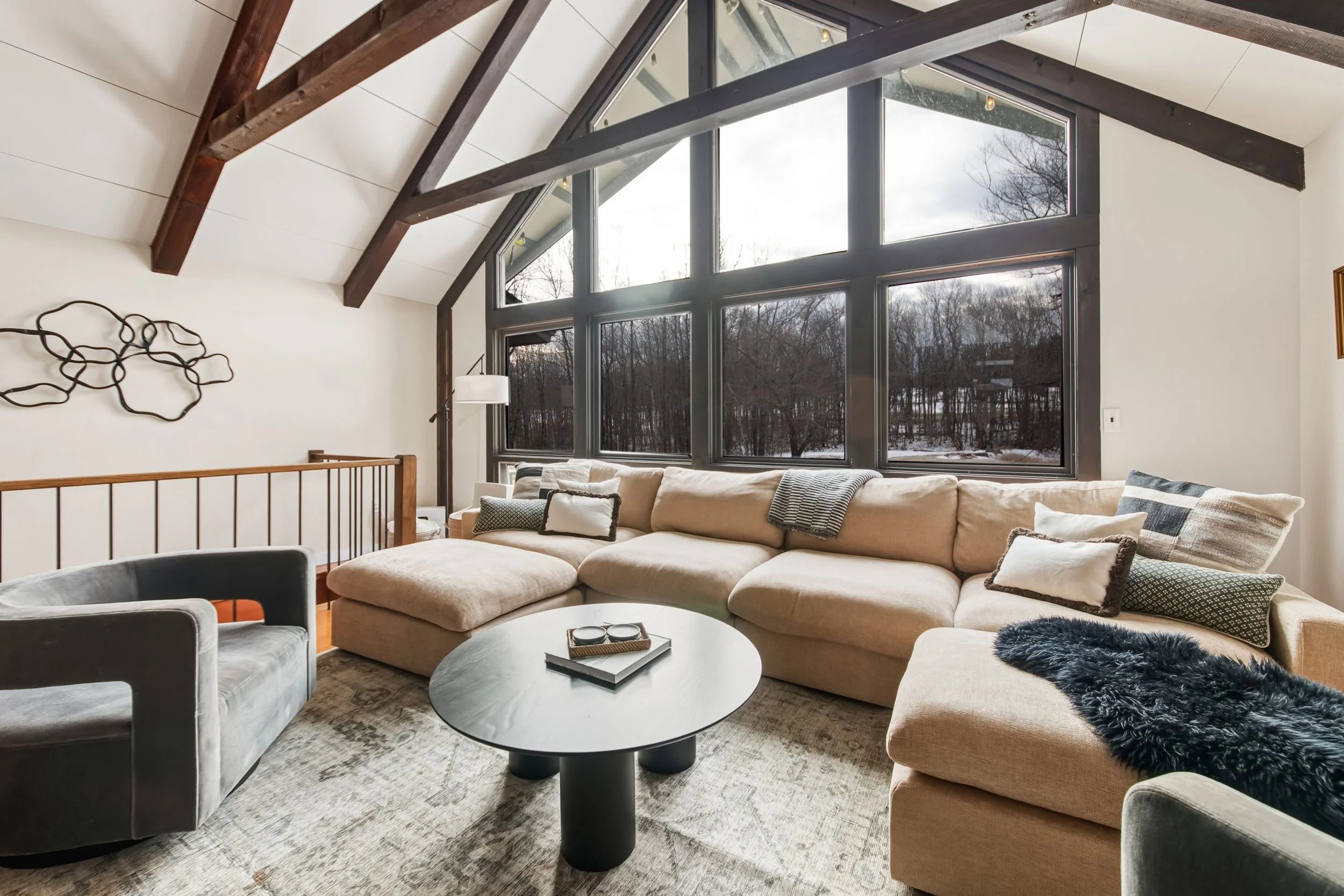 Bright modern living room with large windows, neutral sectional, and natural light — LR Studio interior design