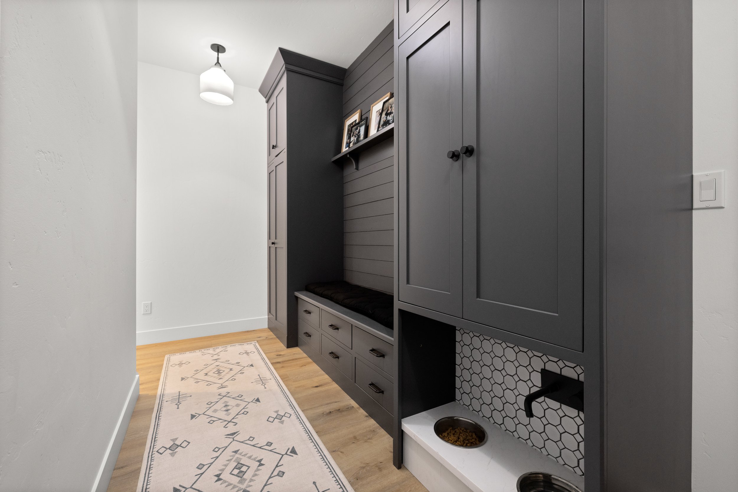 Contemporary entryway with dark built-in storage and geometric rug — LR Studio home styling