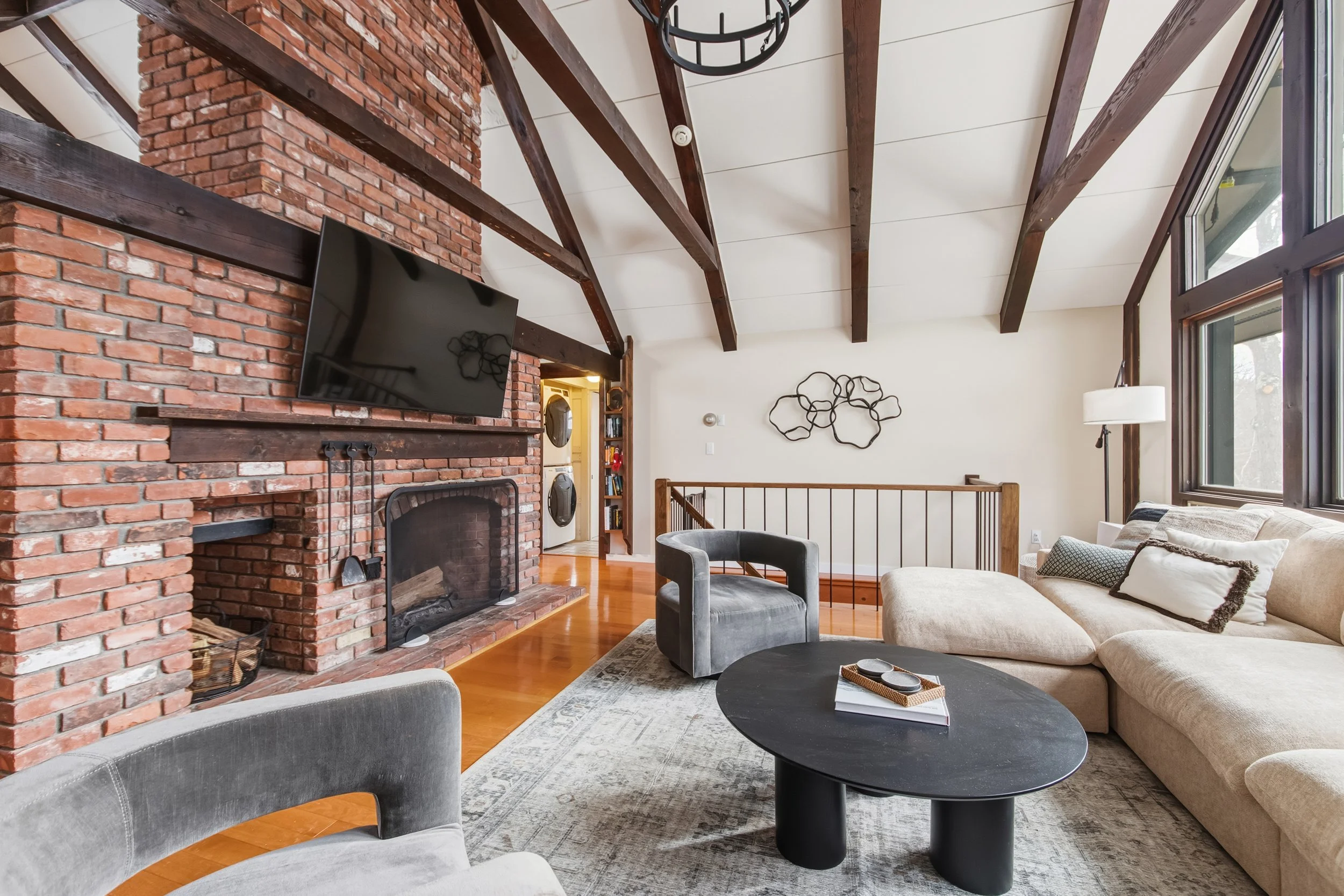 Rustic living room with exposed brick fireplace, wood beam ceiling, and velvet sectional — LR Studio styling