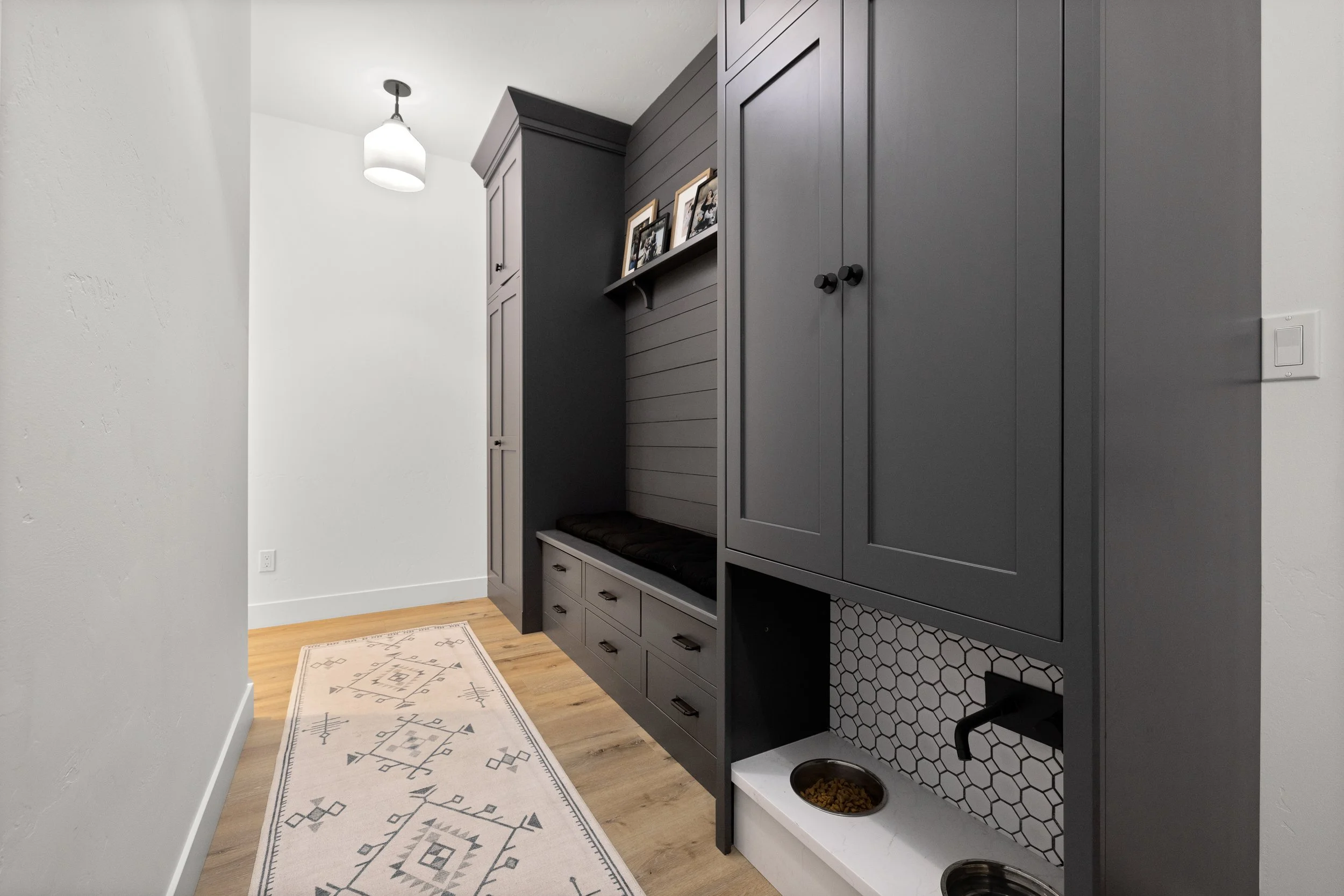 Styled mudroom with dark built-in storage, geometric tile, and patterned runner — LR Studio interior design