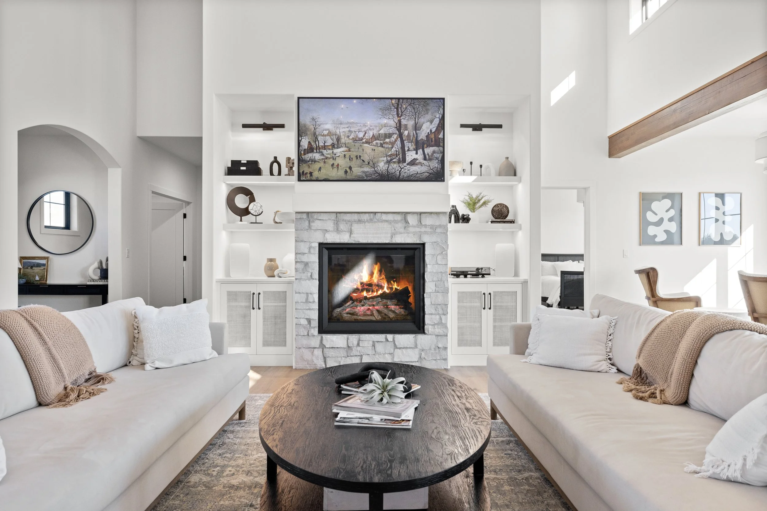 Warm living room with stone fireplace, built-in shelving, and neutral furnishings — LR Studio interior styling
