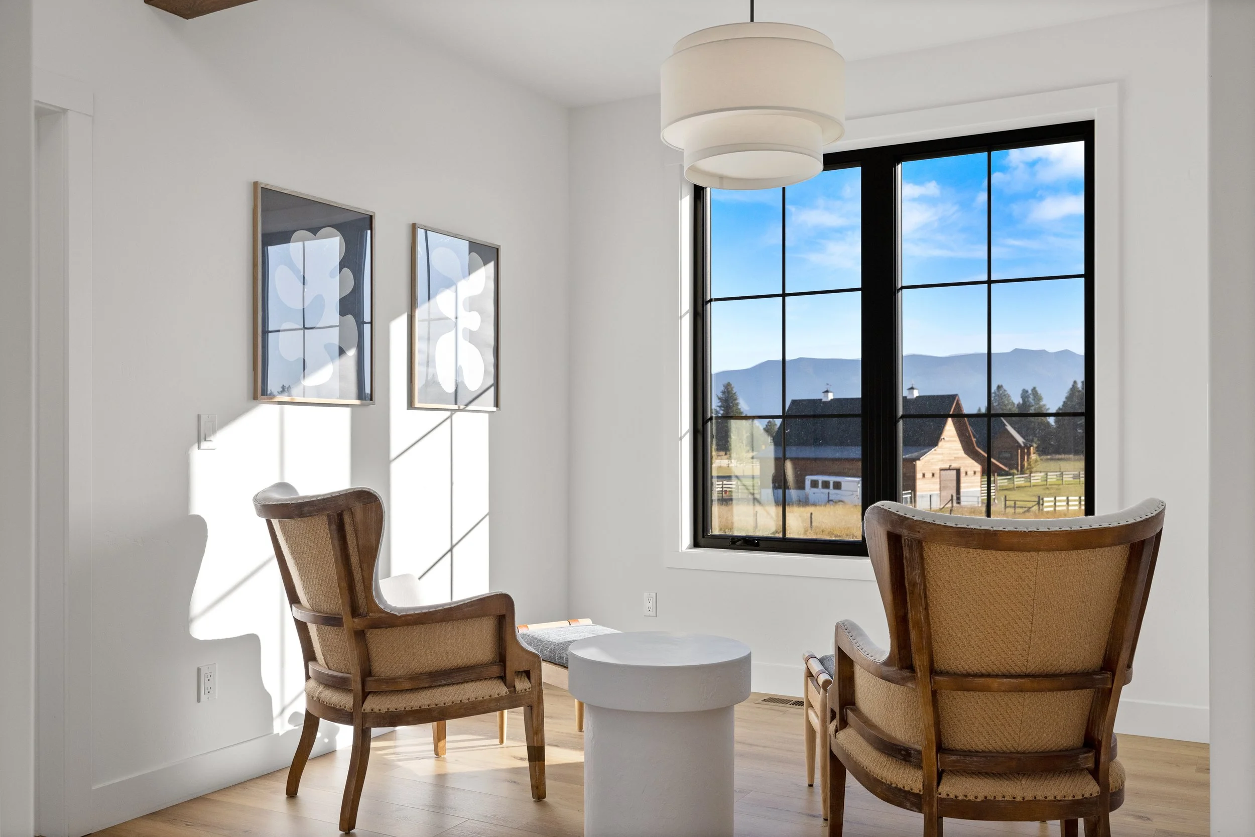 Bright living area with linen accent chairs and large black-paned windows — LR Studio interior design, West Hartford CT