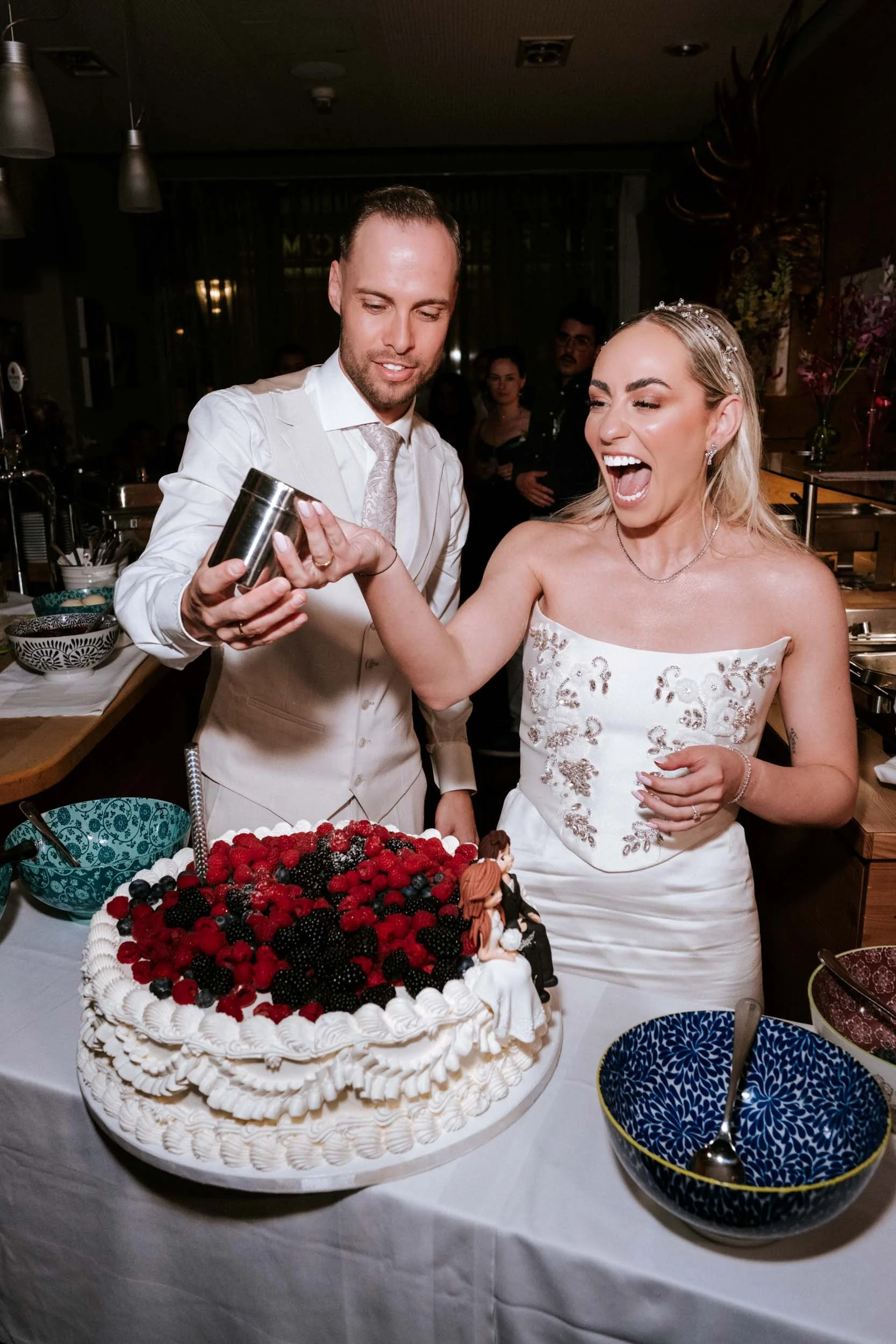 Brautpaar streut Zucker auf die Hochzeitstorte mit frischen Beeren im Hotel Babenbergerhof Mödling