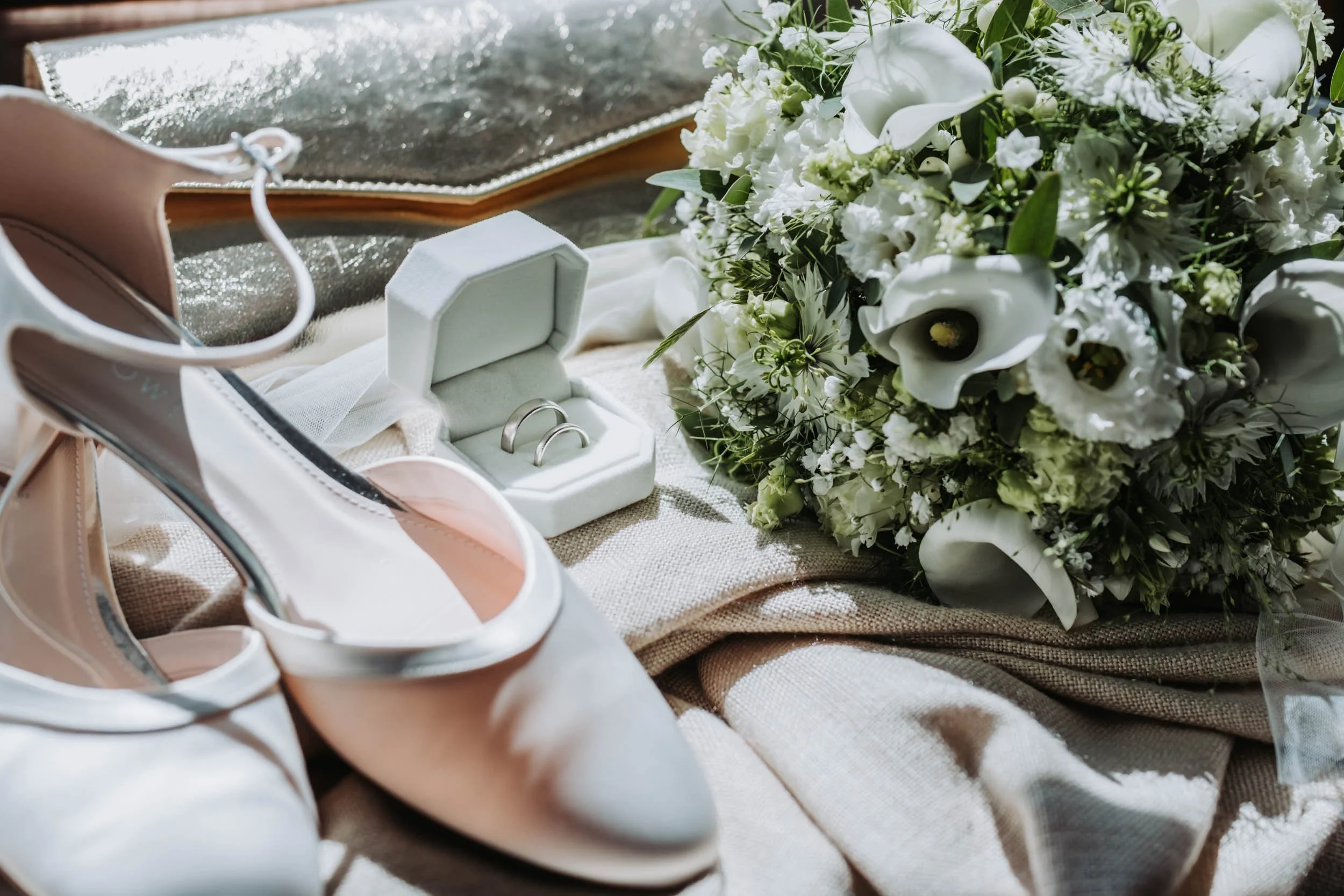Brautschuhe, Eheringe in weißer Schatulle und Brautstrauß mit Callas als Detailaufnahme einer Hochzeit in Wien