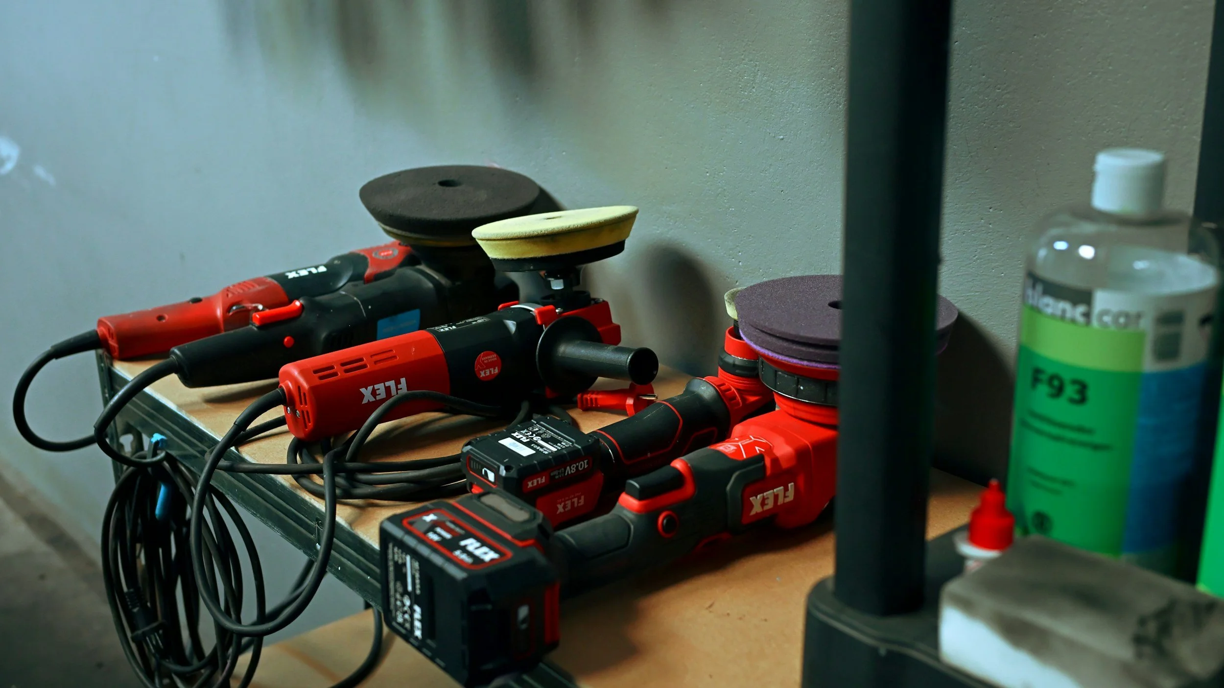 Workshop table with red and black power tools, polishing pads, and cleaning supplies.