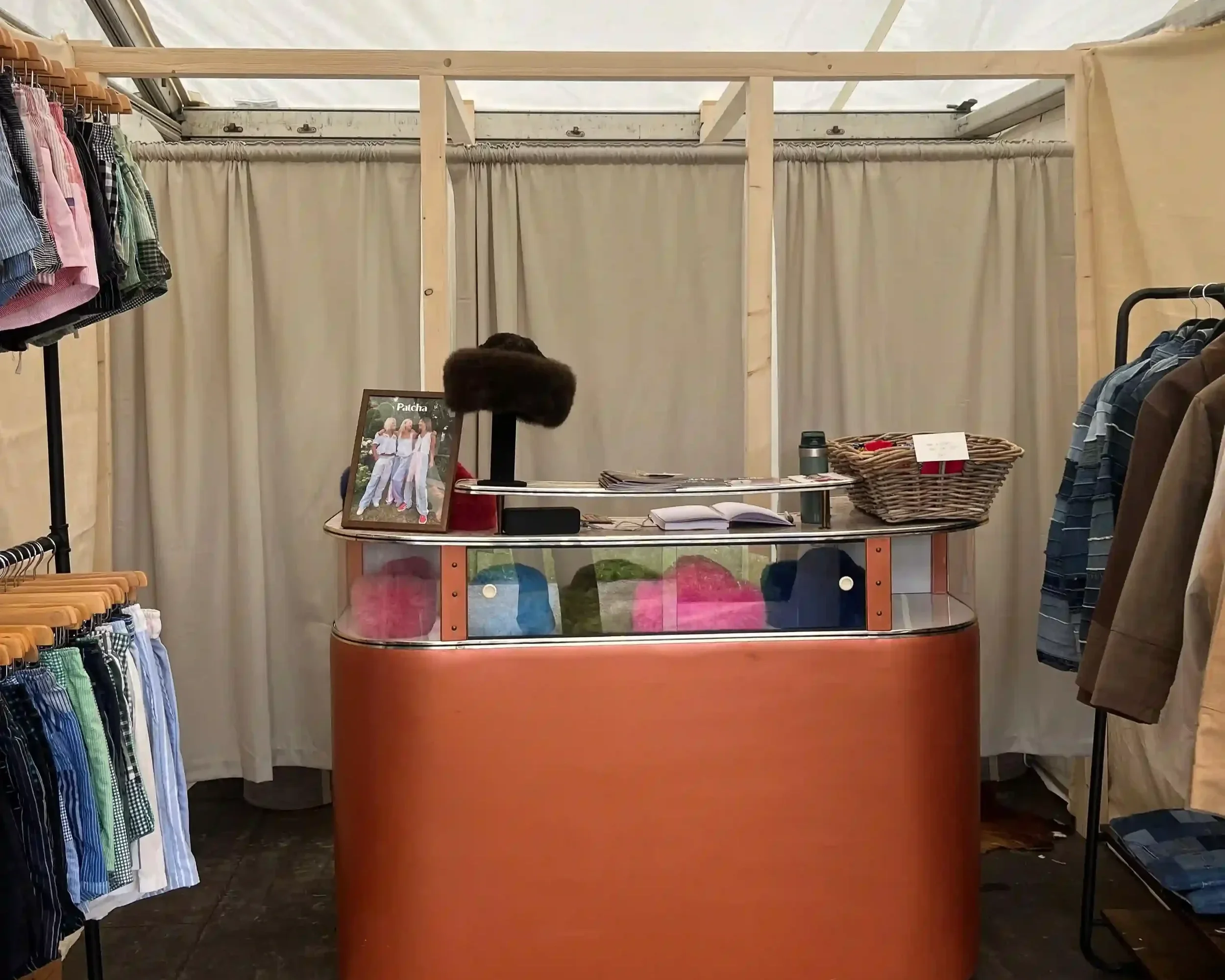 Patcha London bespoke event stand interior with oval terracotta counter, track lighting and clothing rails inside festival marquee