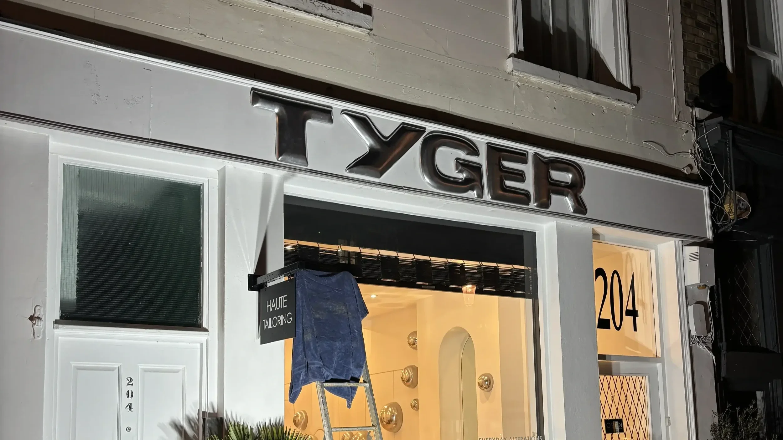 Guests gathered outside Tyger pop-up store at night launch event with silver balloon window display and atmospheric lighting