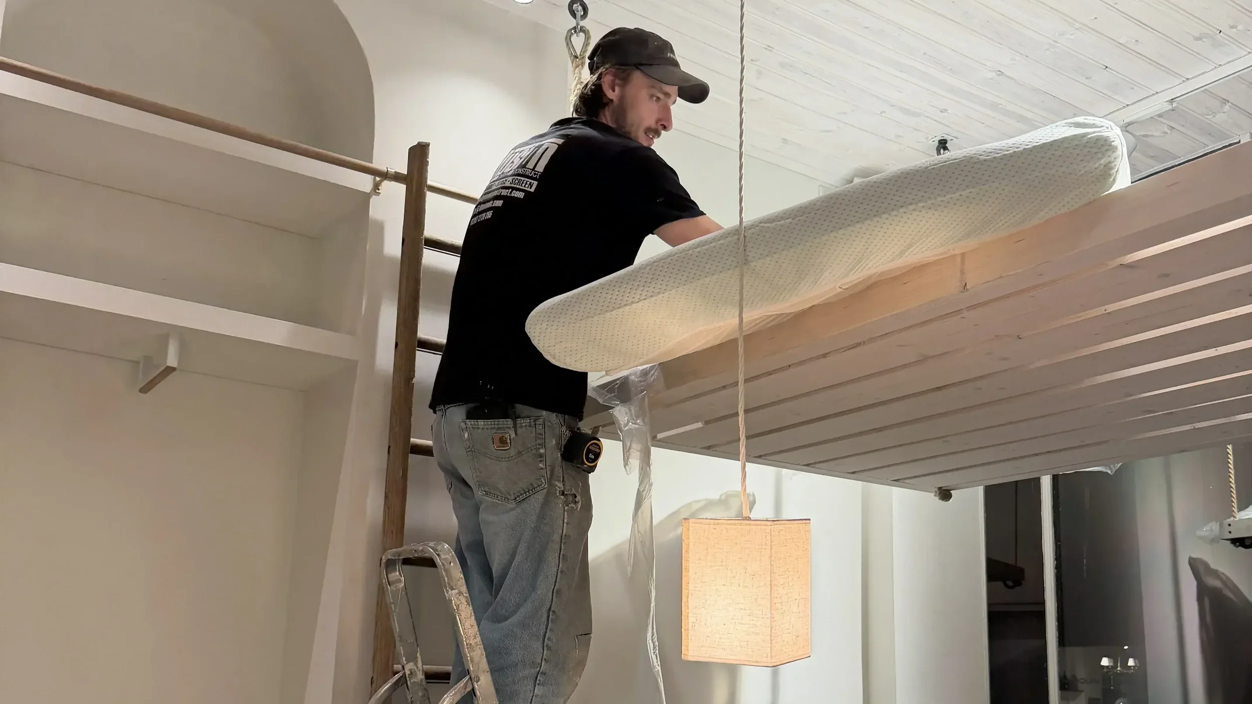 Craftsman on ladder installing bespoke suspended ceiling element in Tom's Trunks retail interior with pendant lamp and arched alcove