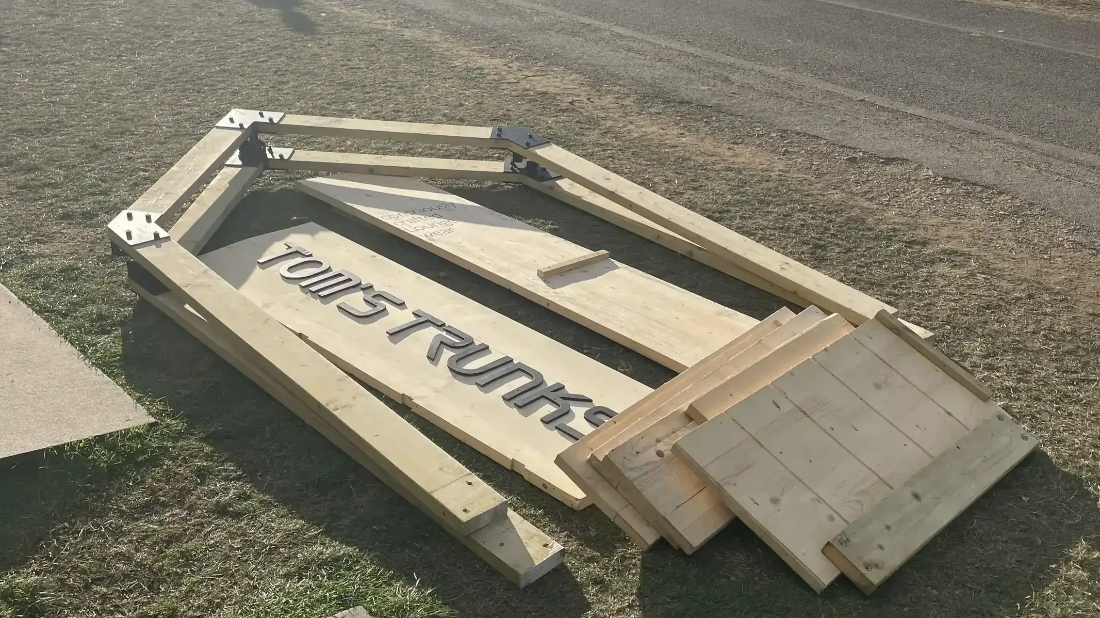 Tom's Trunks bespoke branded wooden fascia panel laid out on grass at festival during brand activation installation
