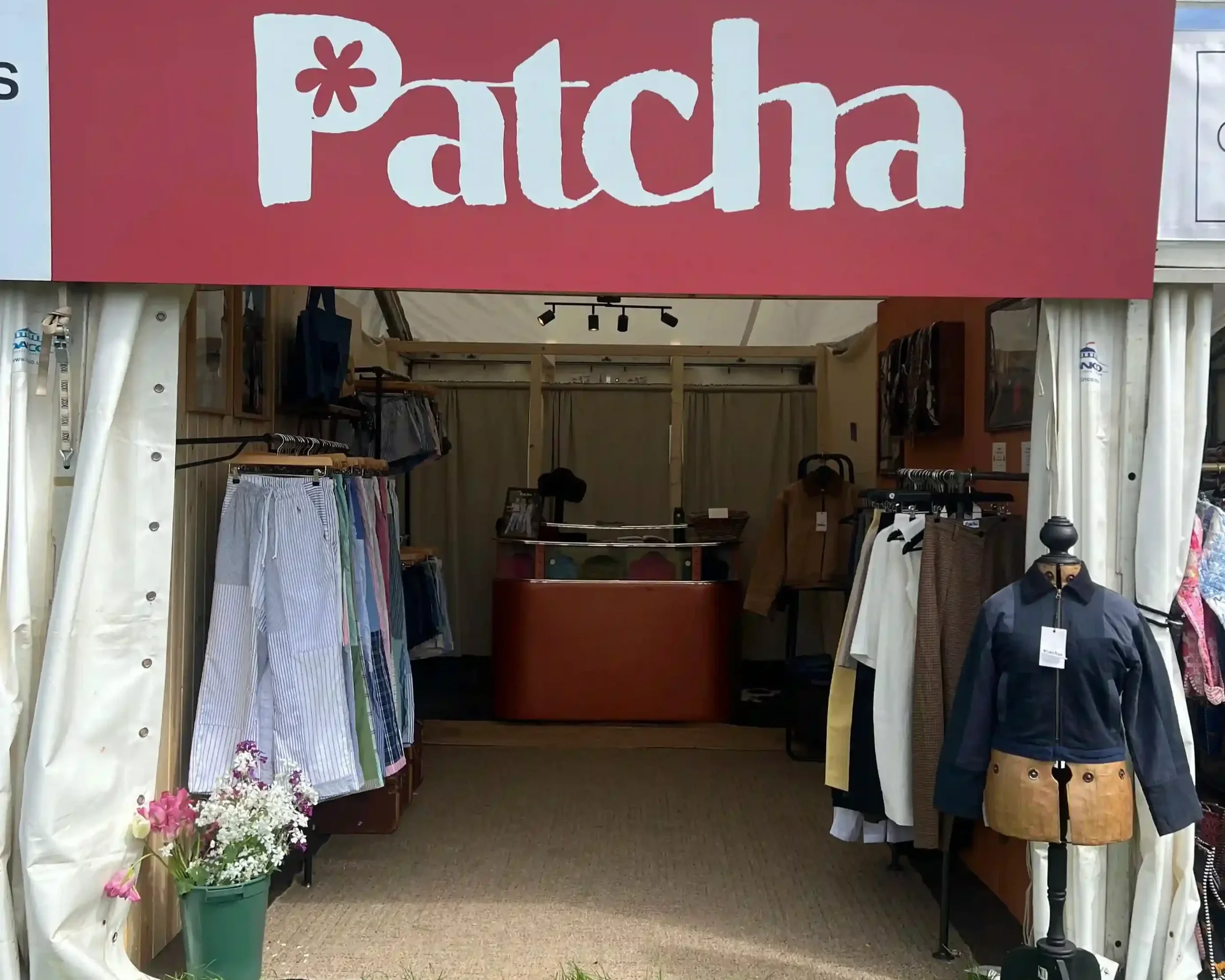 Patcha London pop-up event stall with bold red branded fascia and garments on display rails at outdoor festival