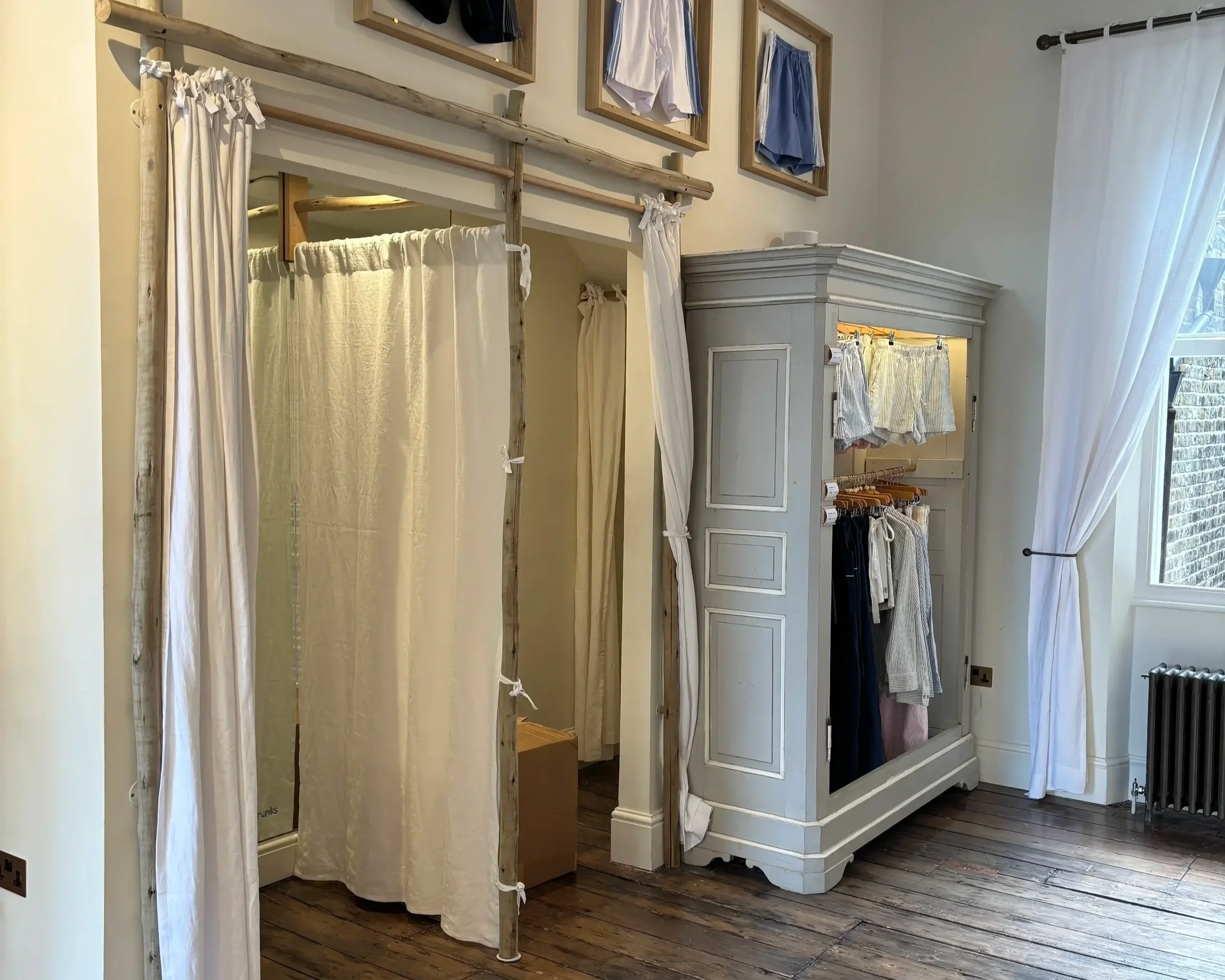 Tom's Trunks bespoke retail interior with rustic pole changing rooms, natural linen curtains and framed product wall displays
