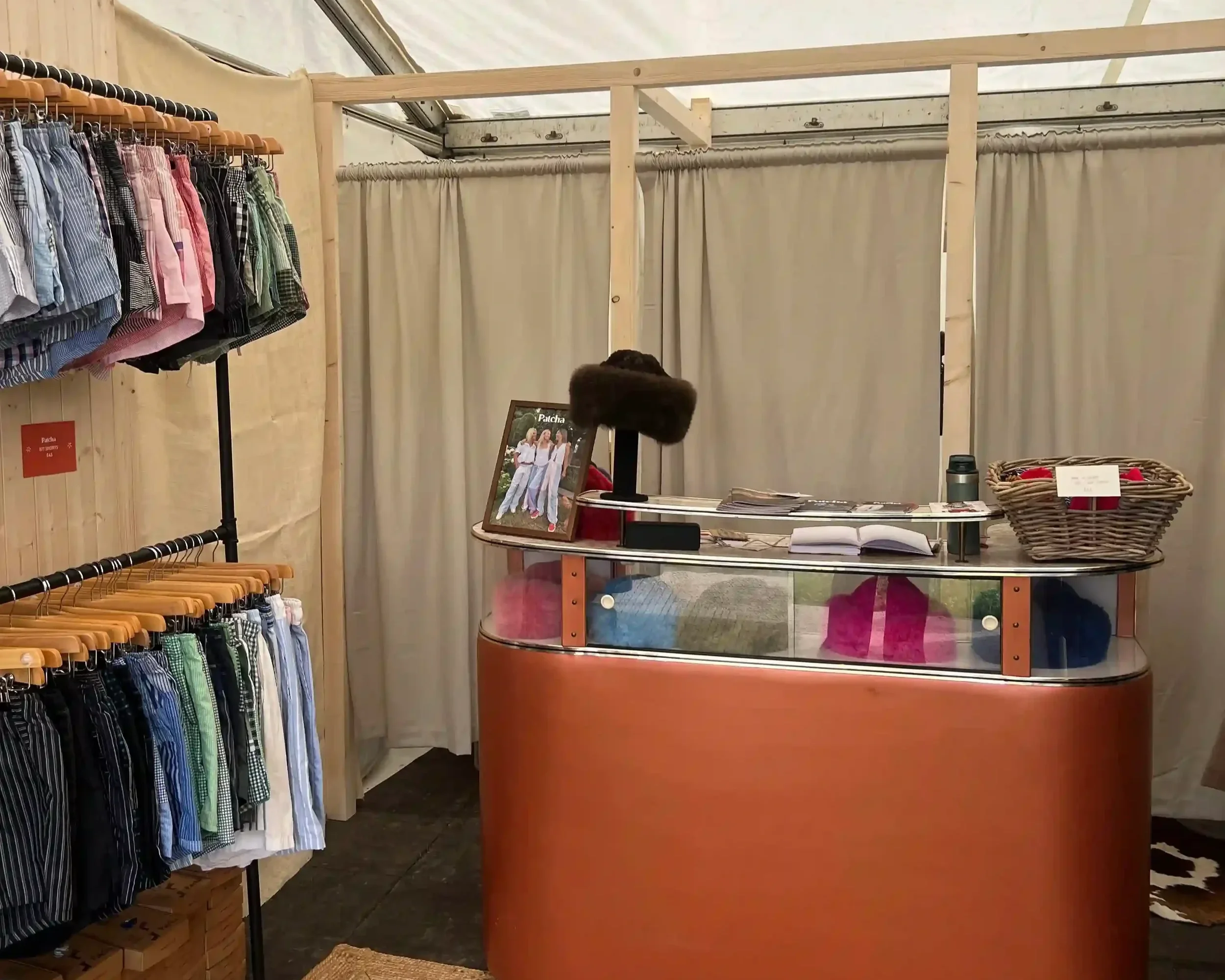 Patcha London bespoke event retail stand interior with oval terracotta counter and colourful clothing racks inside a marquee tent