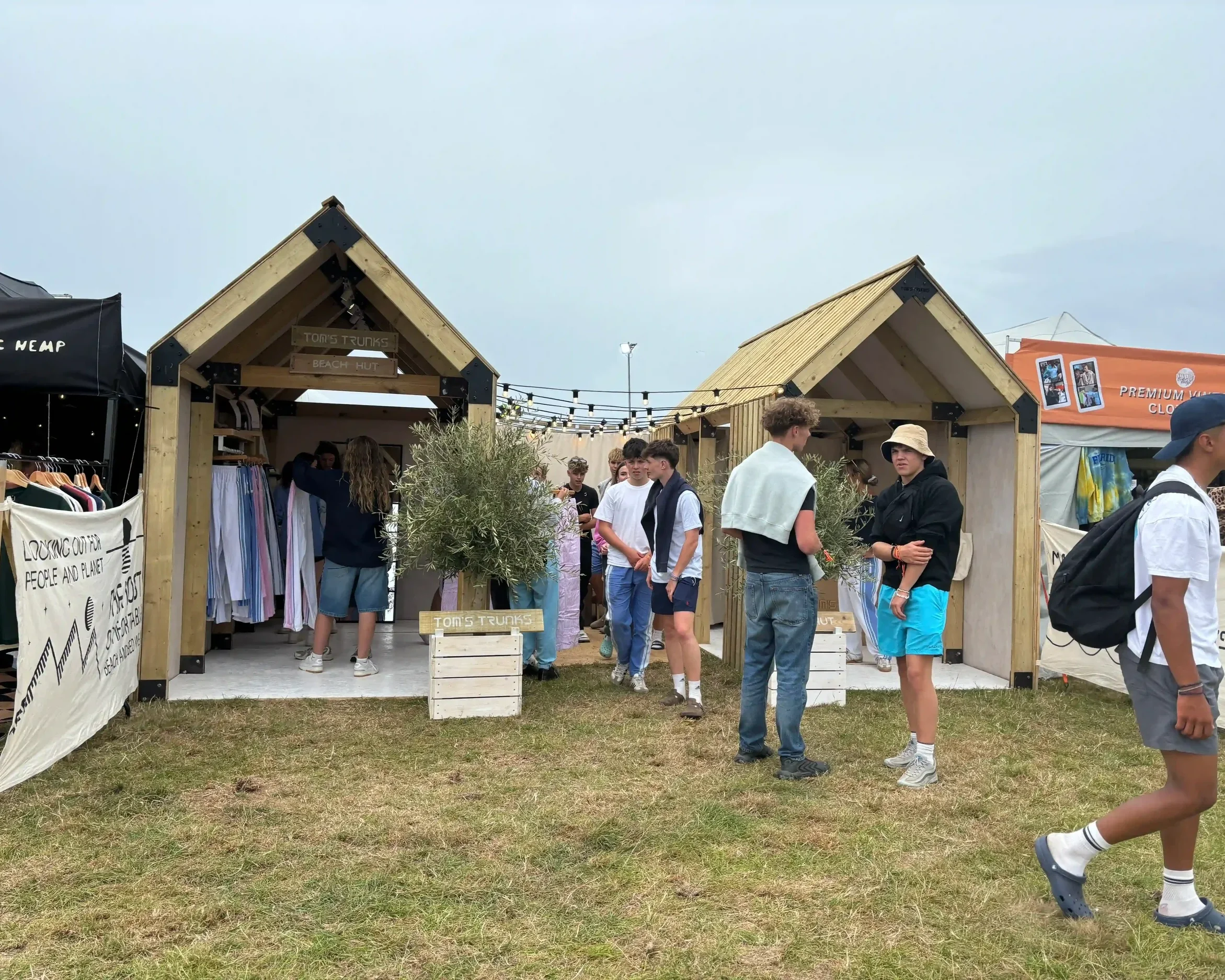 Customers browsing Tom's Trunks bespoke wooden beach hut brand activation stalls at a busy outdoor festival