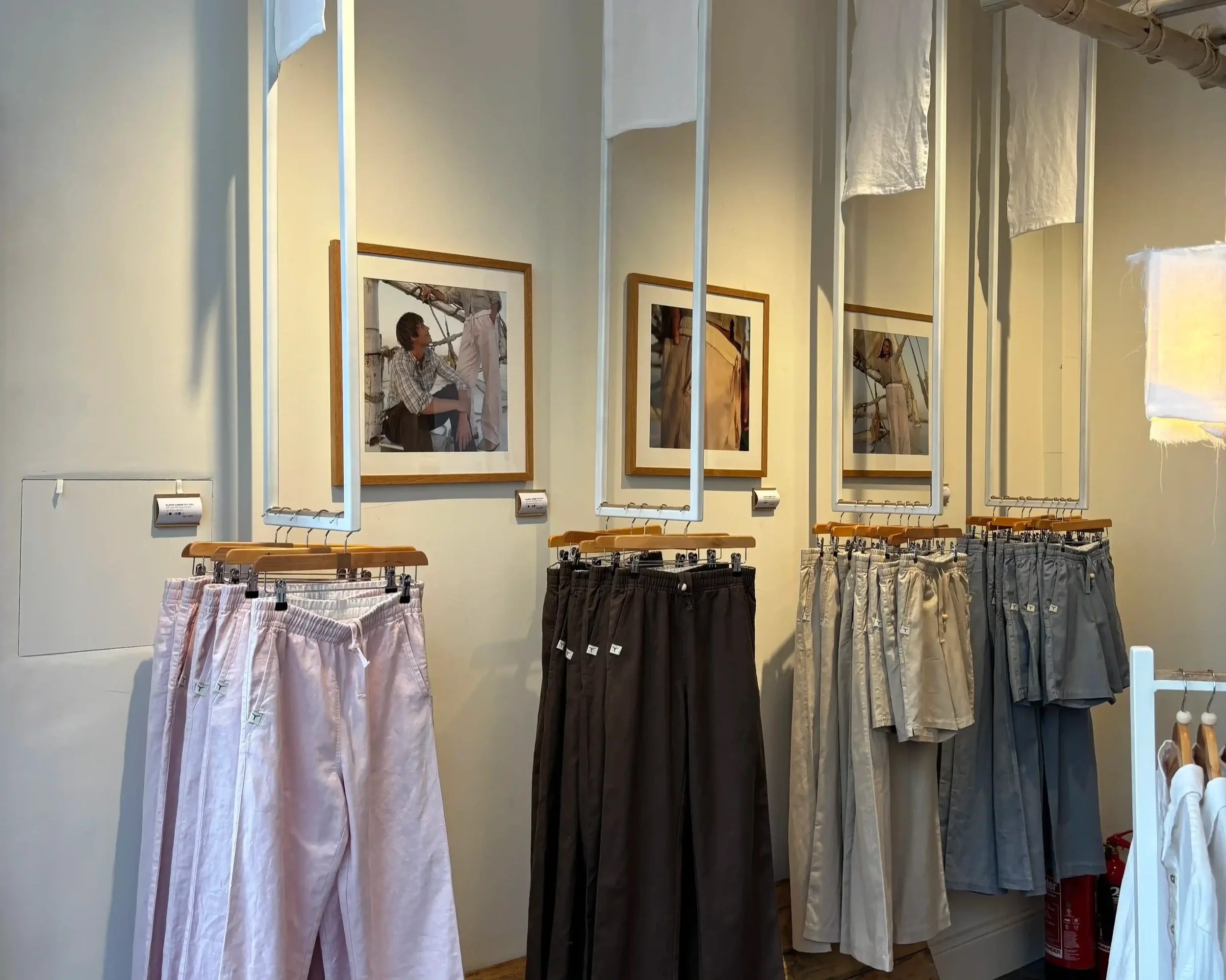 Tom's Trunks bespoke retail interior with wide-leg trousers on suspended rails and framed photography prints on grey wall