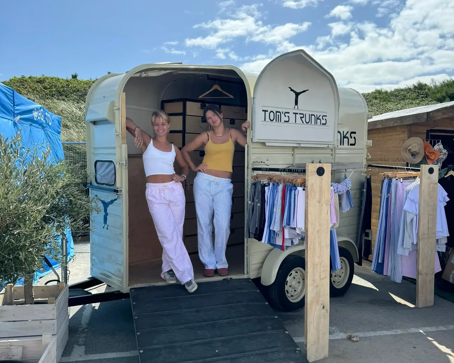 Two customers browsing clothing at Tom's Trunks branded horsebox mobile brand activation unit at outdoor festival