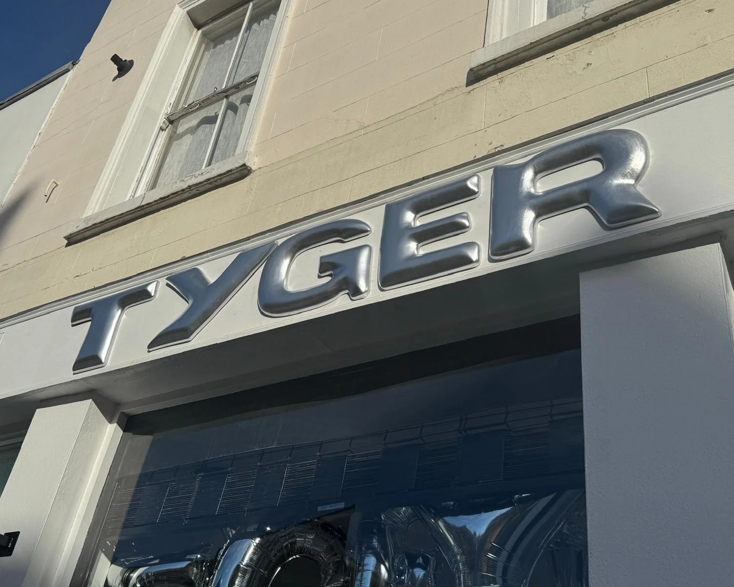 Detail shot of Tyger pop-up brand activation with oversized silver foil balloon letters filling the shopfront window display