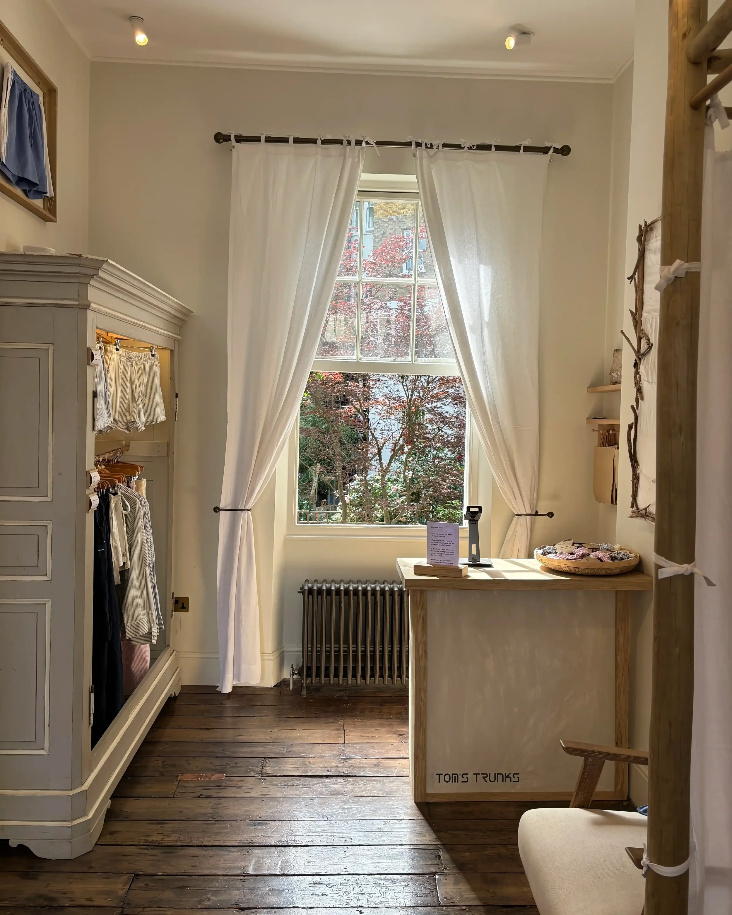 Tom's Trunks bespoke retail interior with natural light through sash window, vintage wardrobe and branded wooden sales counter