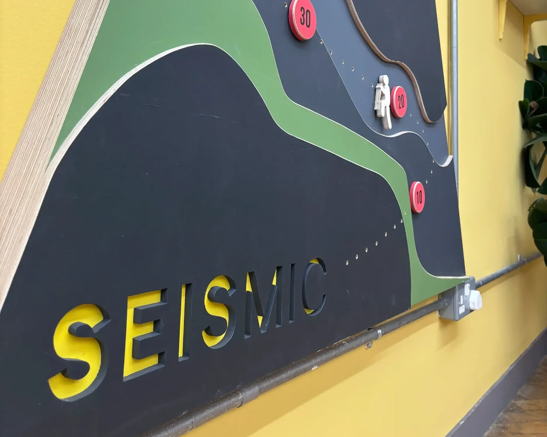 Close-up detail of Seismic bespoke triangular display board with topographic mountain graphic and branded yellow lettering