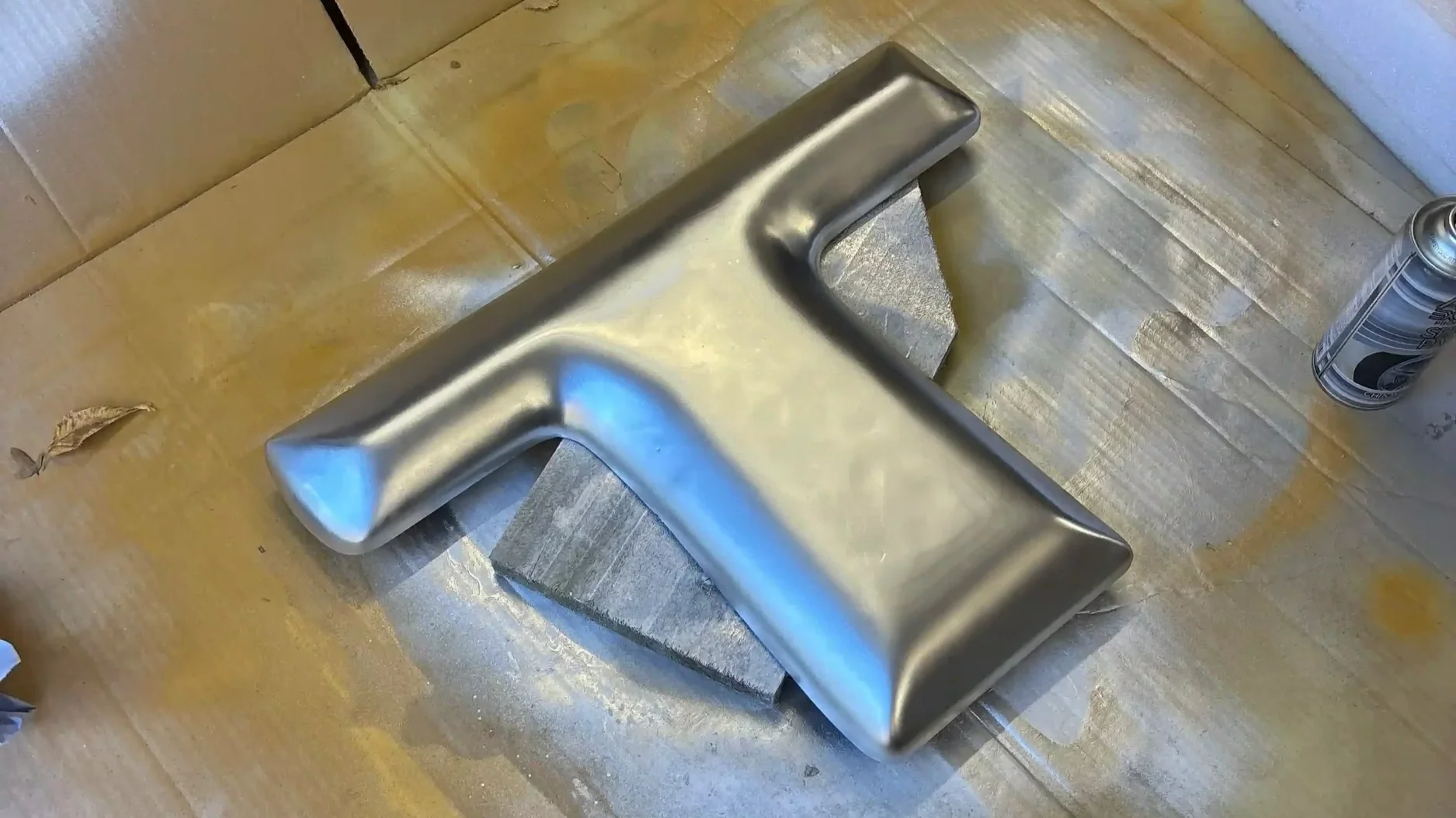 Bespoke chrome metal component being spray painted in workshop during custom fabrication process for brand activation build