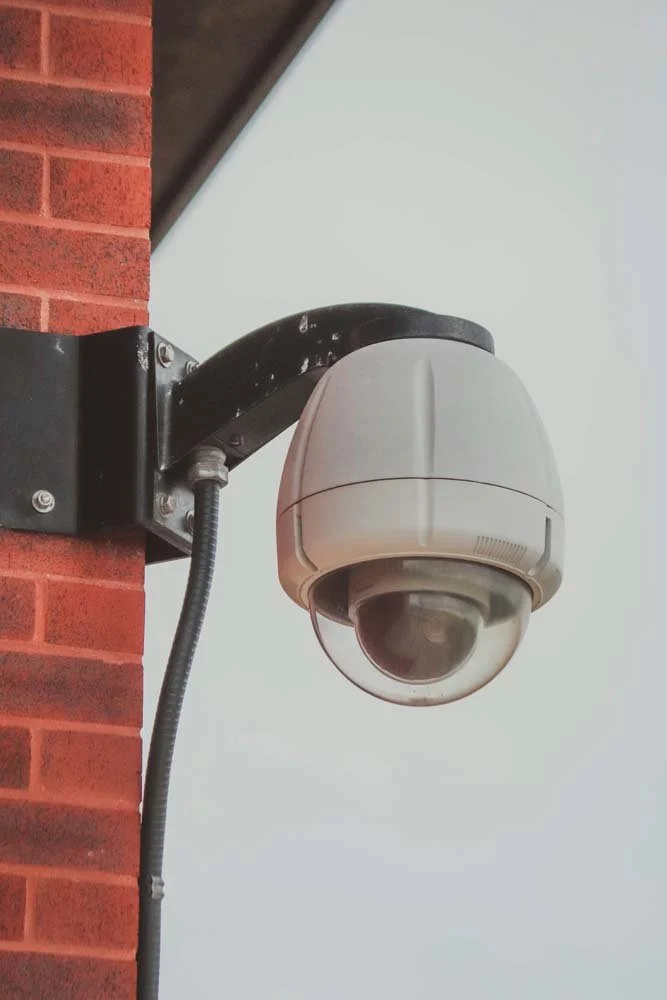 Security camera mounted on a brick wall.