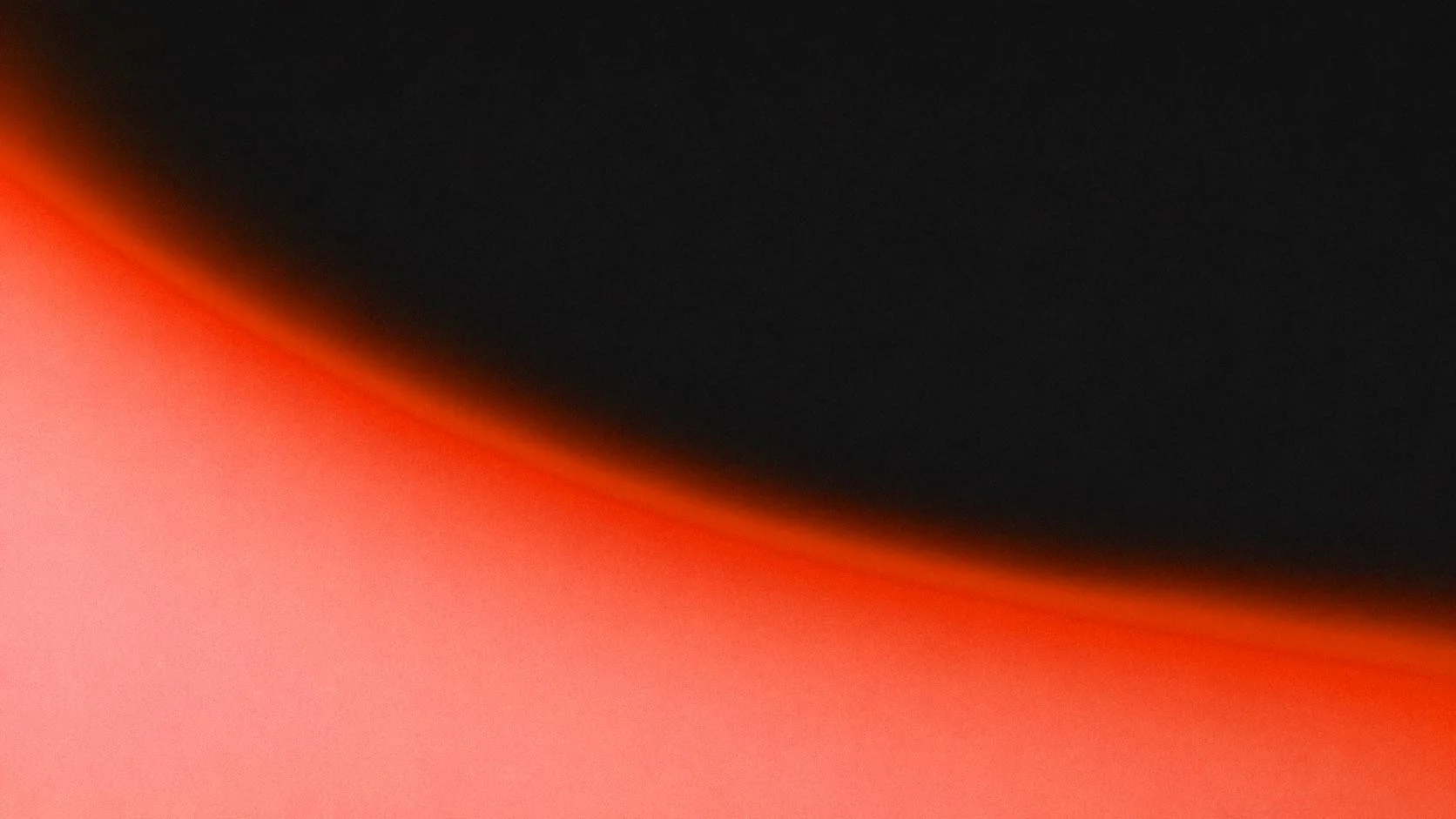 Abstract close-up of an object with black, red, and orange colors blending together.