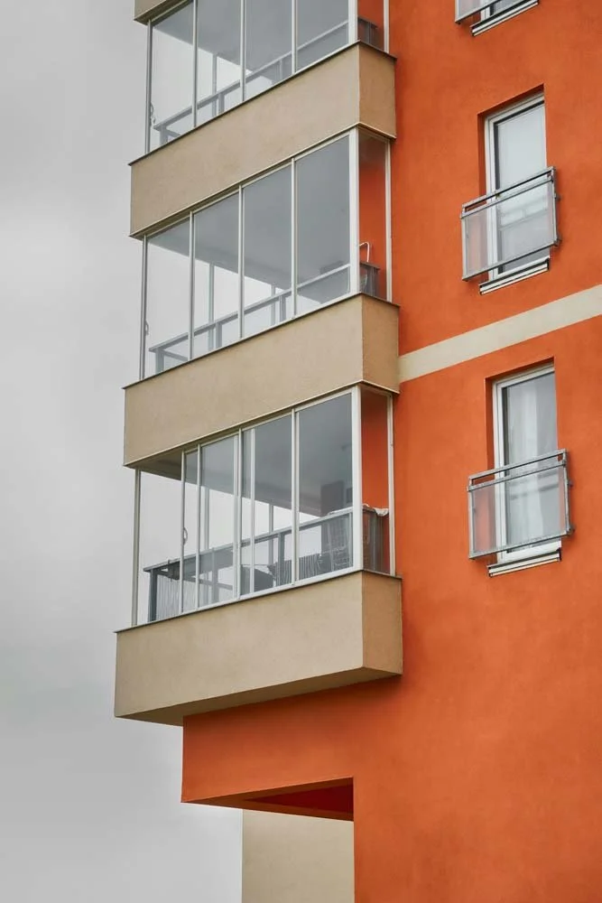 Close-up of a modern residential building with glass-enclosed balconies and orange exterior walls.